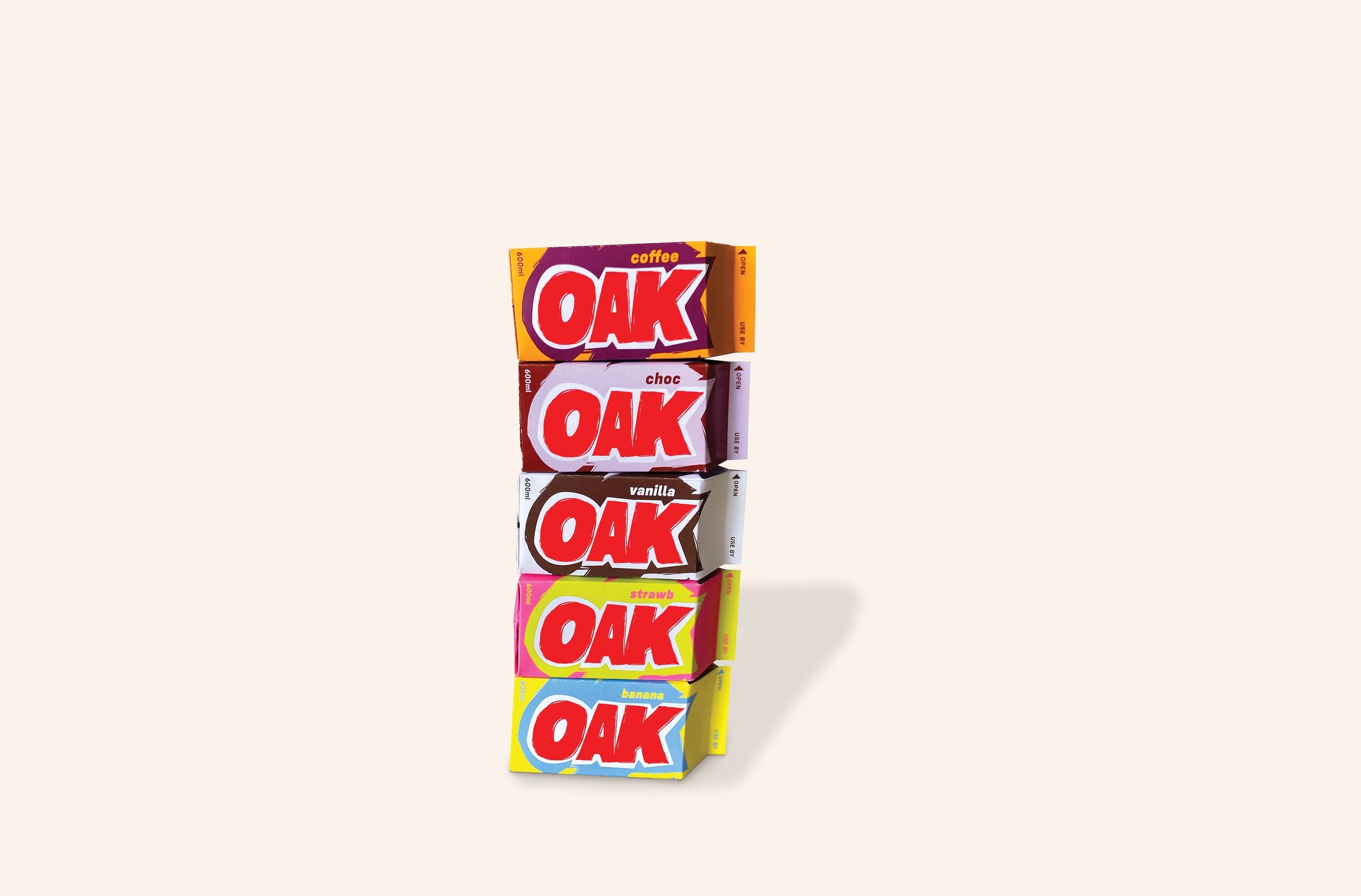 Stack of five OAK flavoured milk cartons arranged vertically, displaying different flavour variants: coffee (orange), choc (red), vanilla (brown), strawberry (pink), and banana (yellow). Each carton features the bold red 'OAK' logo against its flavour-specific coloured background.