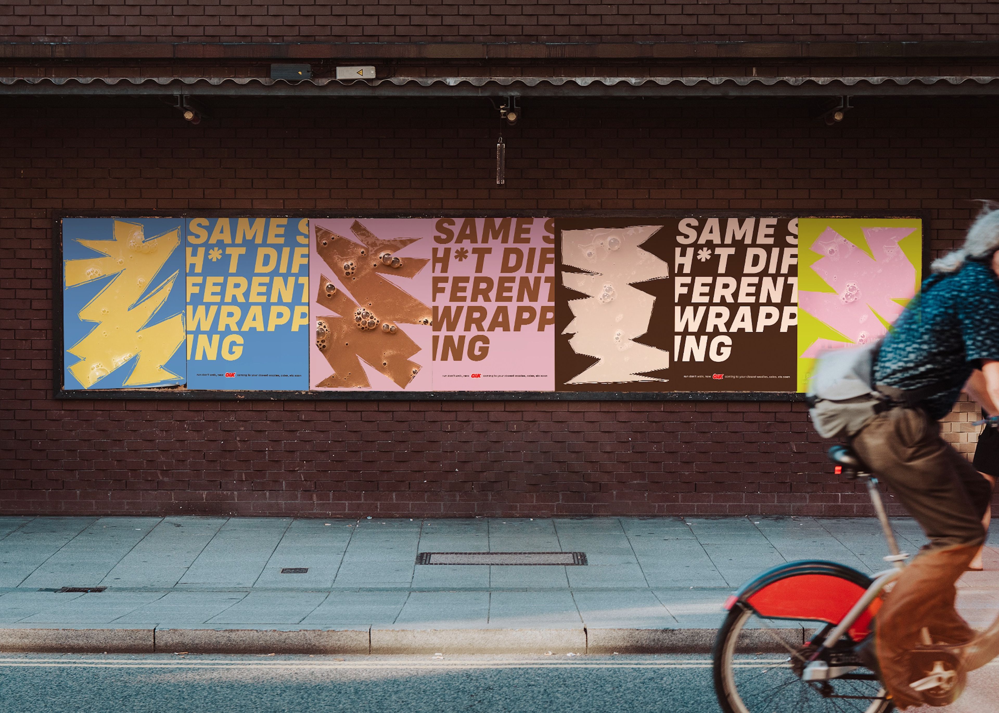 Outdoor wall with a series of posters with the phrase "Same Sh*t Different Wrapping" in various colours and layouts, accompanied by stylised graphics. A cyclist passes by in the foreground.