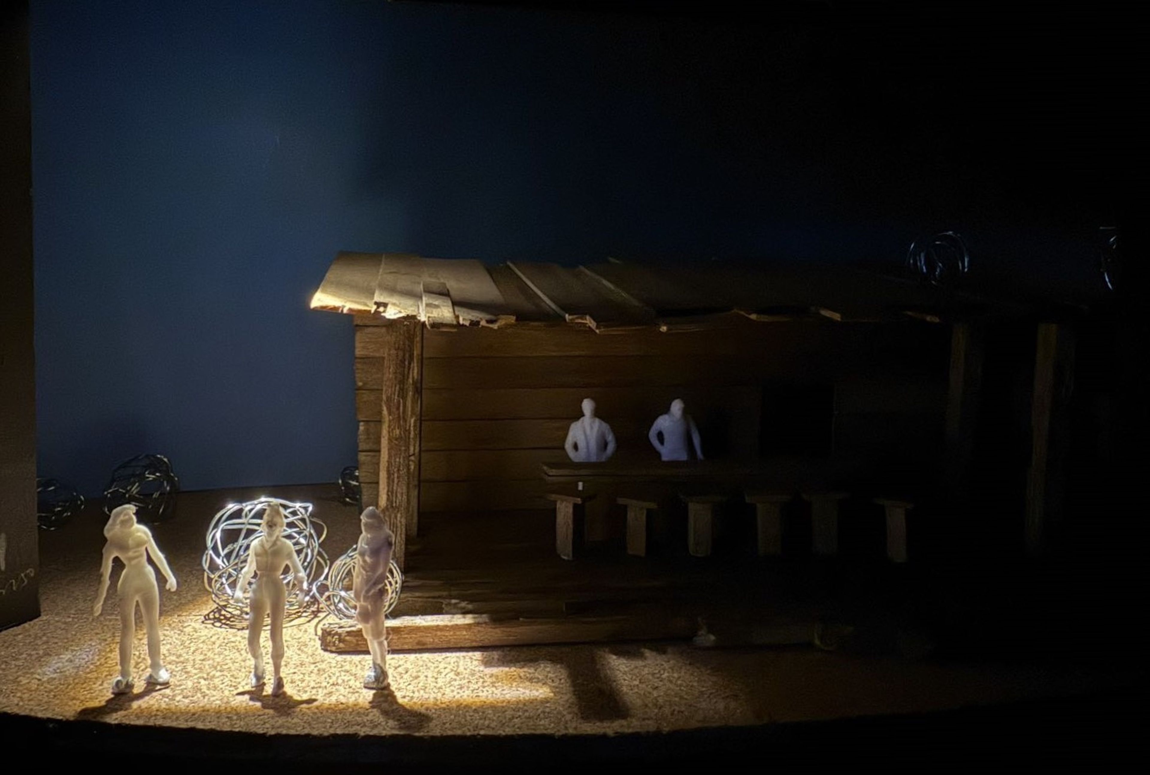 Dimly lit saloon model with three figures in the foreground, standing near the entrance and wire tumbleweeds.