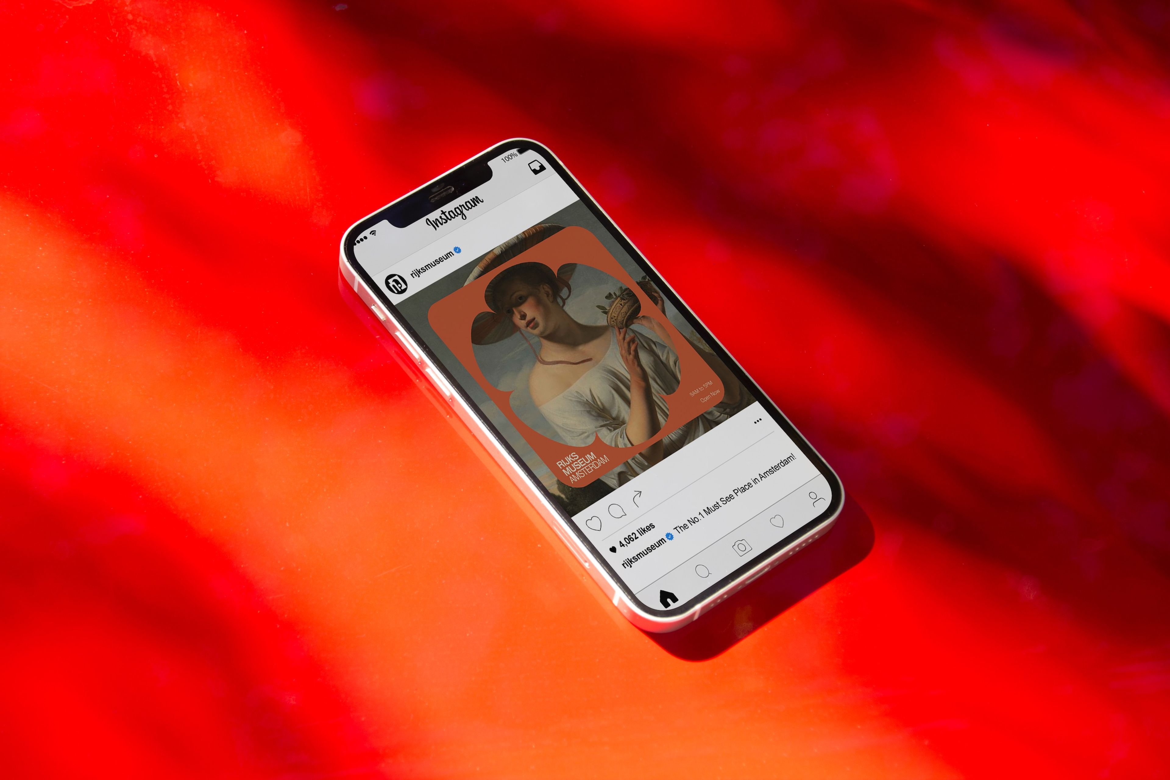 iPhone displaying a Rijksmuseum Instagram post against vibrant red gradient background. The post shows a classical painting in a rounded frame with engagement metrics visible. 