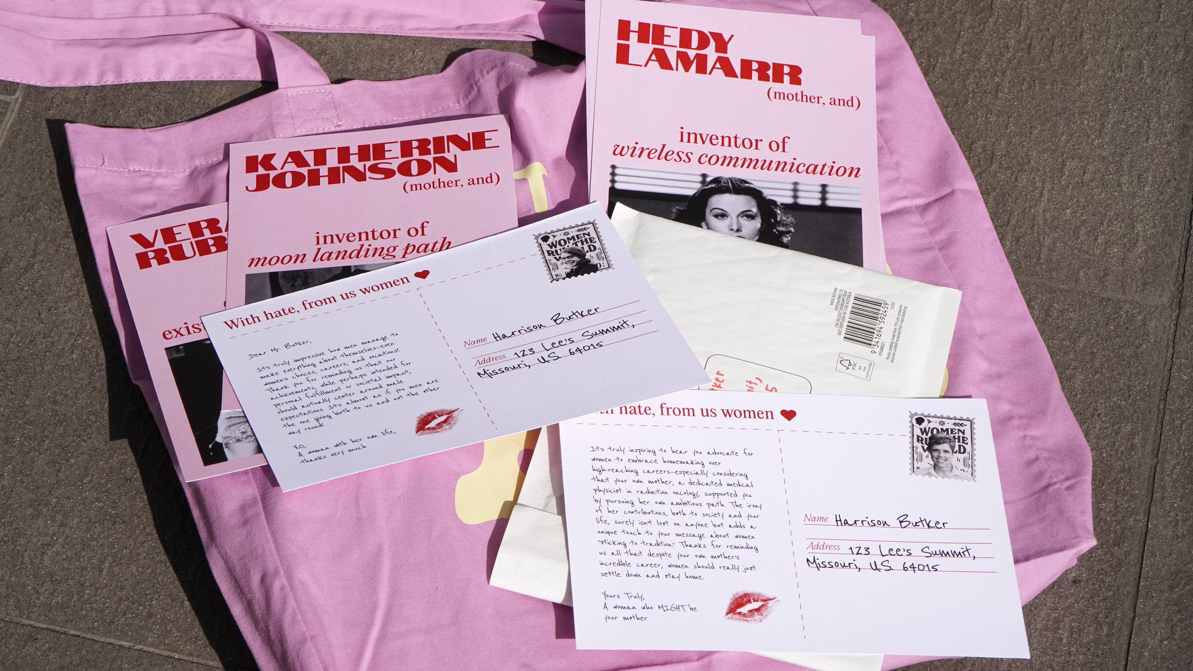 Collection of pink, white and red postcards titled 'With hate, from us women' laid on pink fabric. Features profiles of pioneering women including Katherine Johnson ('inventor of moon landing path') and Hedy Lamarr ('inventor of wireless communication'), signed with red lipstick marks.