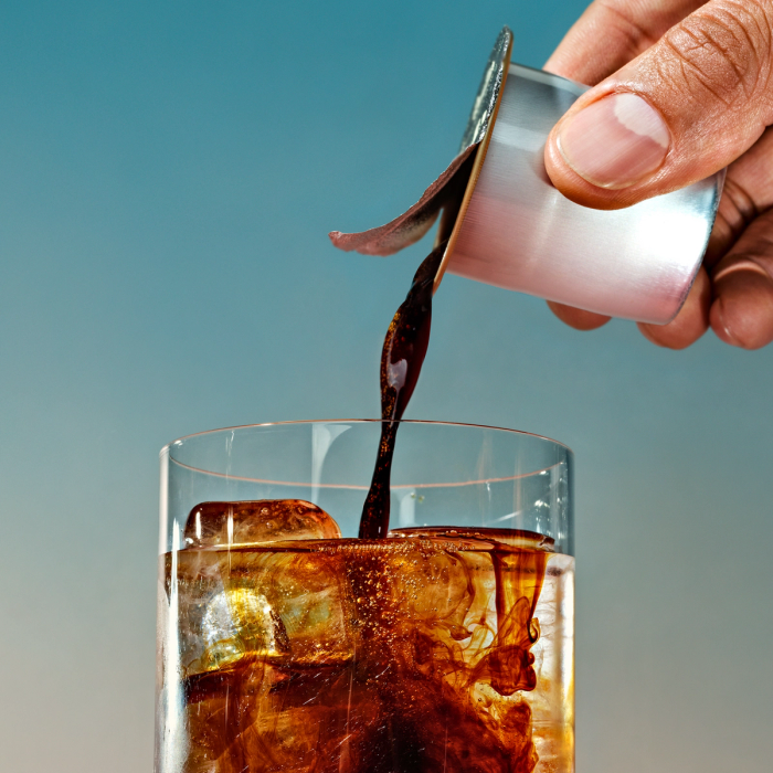 An image of a coffee pod being poured into an 8oz glass of iced water