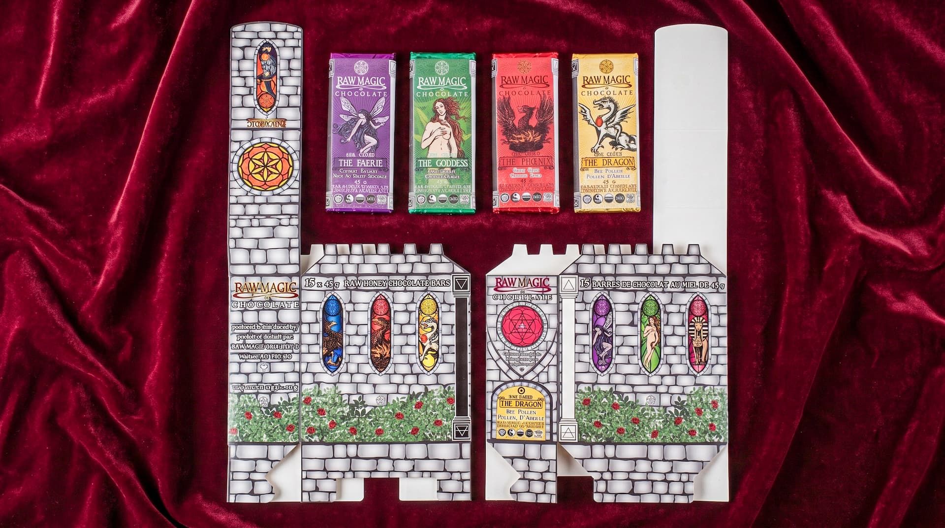 Flat, unfolded castle packaging next to four colorful Raw Magic Chocolate bars on a red velvet backdrop.