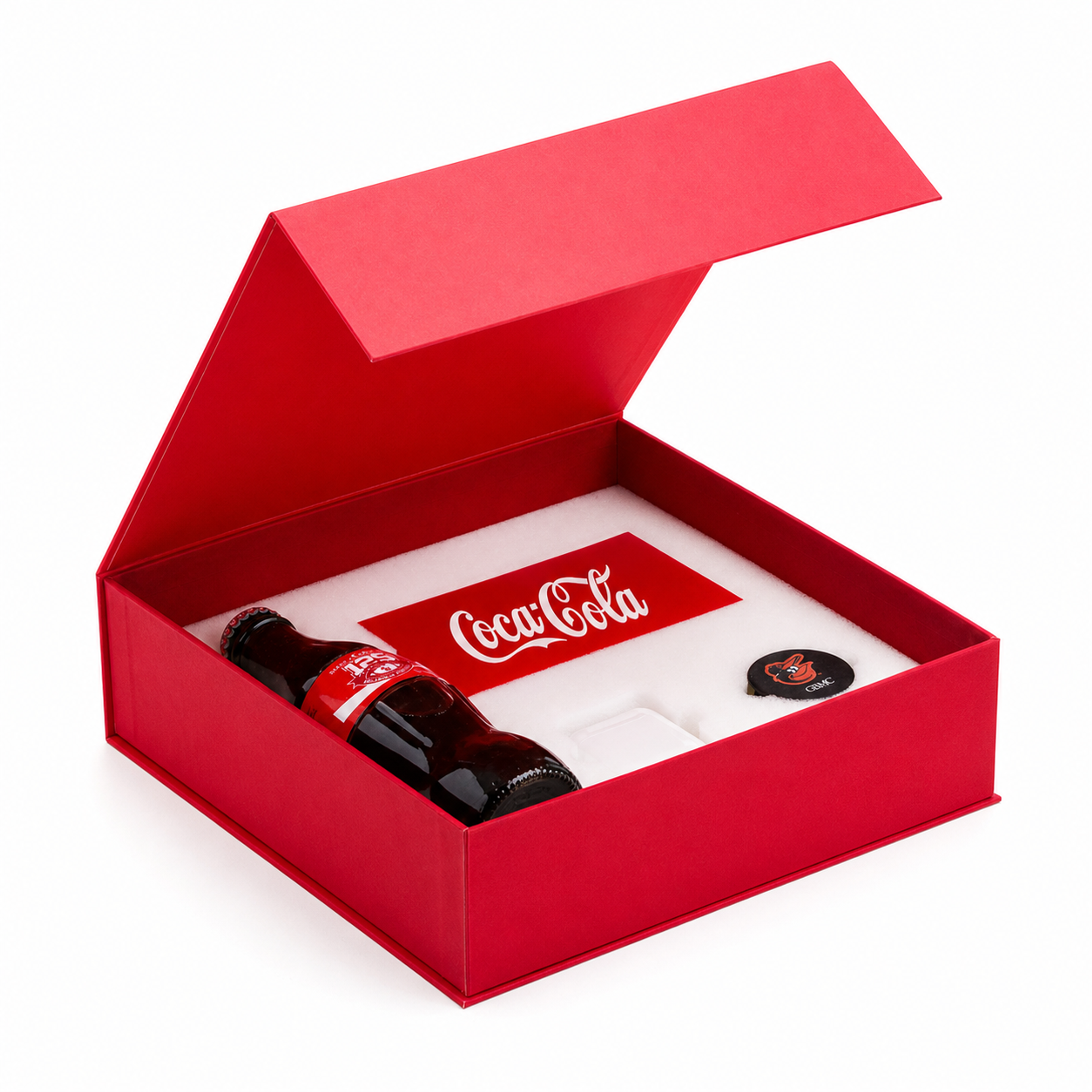 Angled view of an open red Coca-Cola box holding a glass bottle, card, and branded accessories.