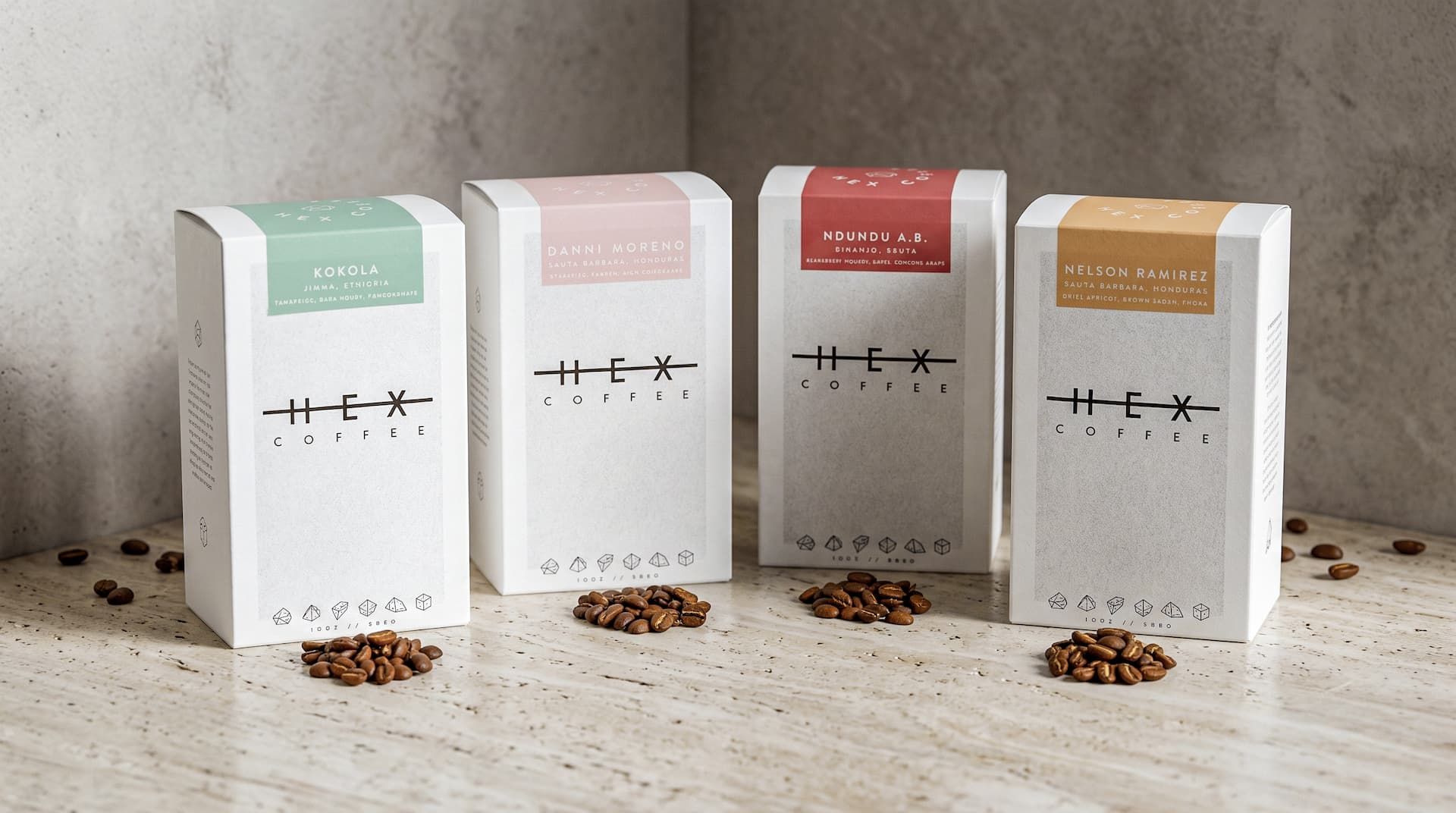 Four Hex Coffee boxes with distinct colored labels standing in a row, each with a small pile of coffee beans in front.