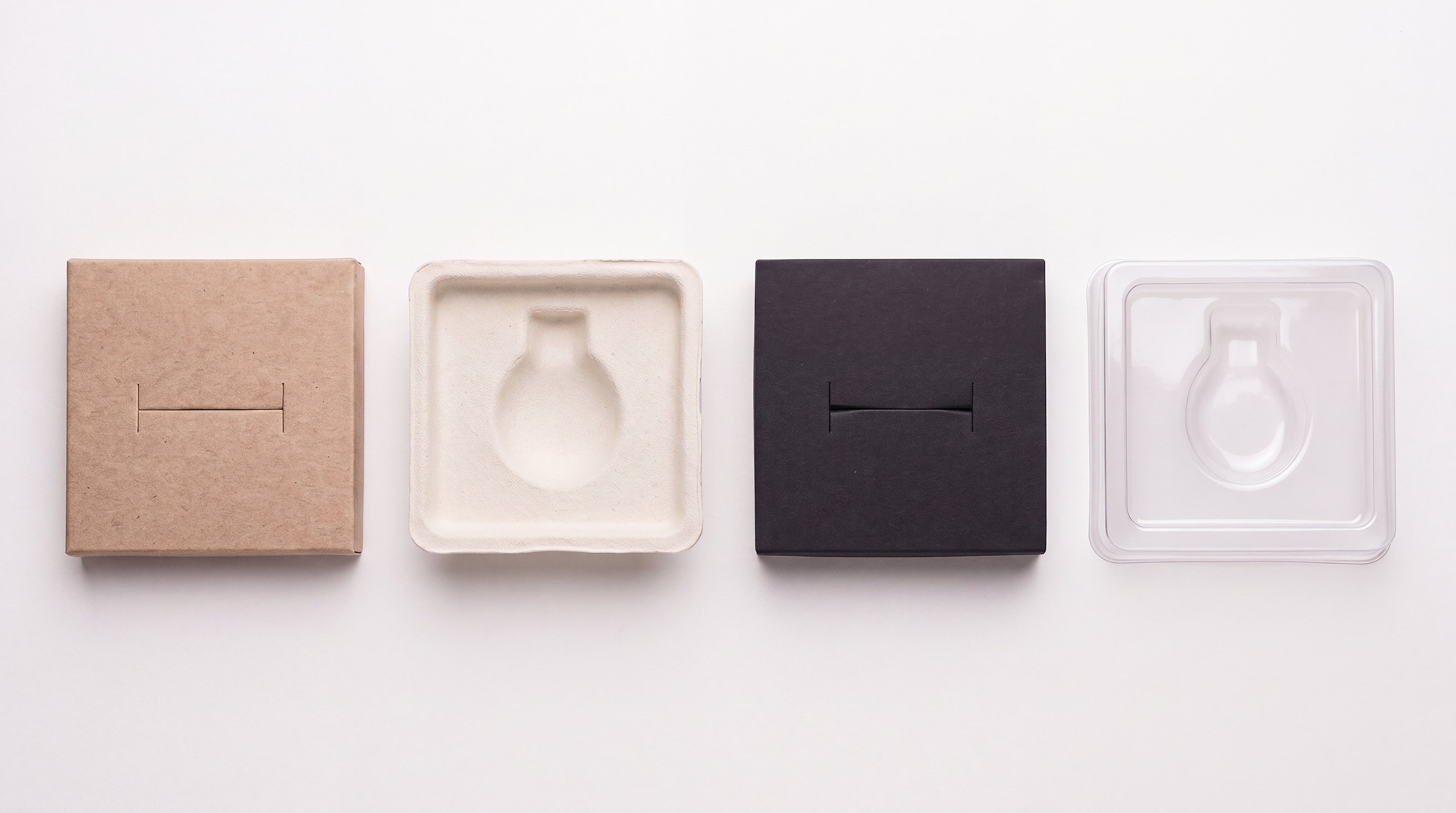 Four jewelry inserts in a row: die-cut kraft card, molded pulp, black foam, and clear vacuum-formed plastic.
