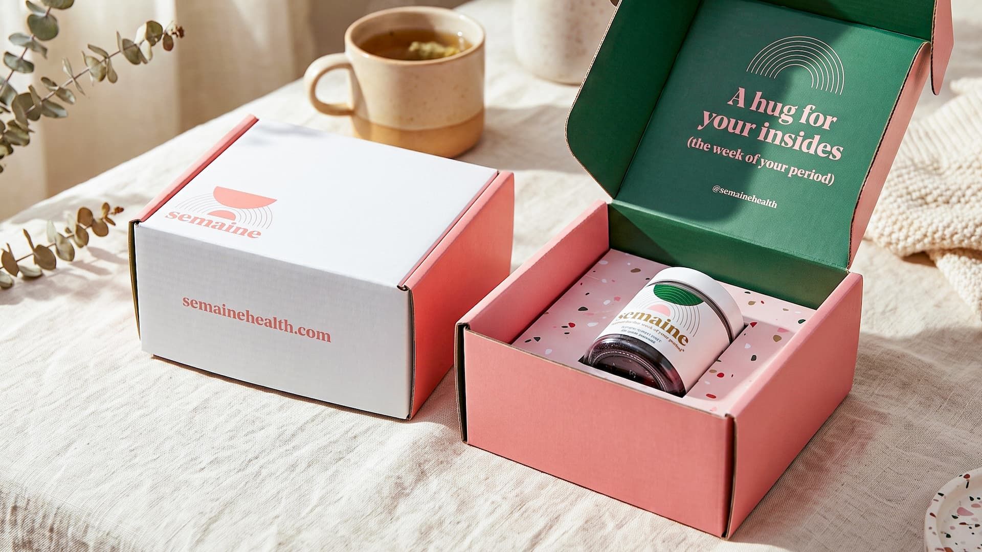 Closed and open Semaine mailer boxes on a table, revealing a green inner lid and a jar in a pink terrazzo insert.