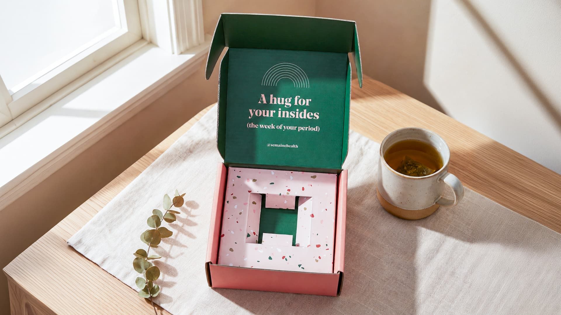 Open Semaine box on a table showing an empty custom pink terrazzo insert designed with cutouts to hold a jar.
