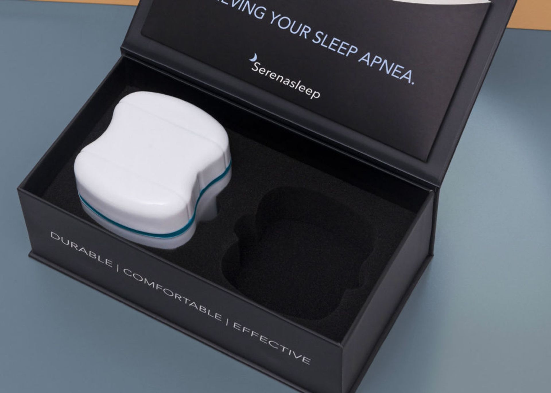 High-angle view of an open Serena Sleep box showing a white device case inside a dual-cavity black foam insert.