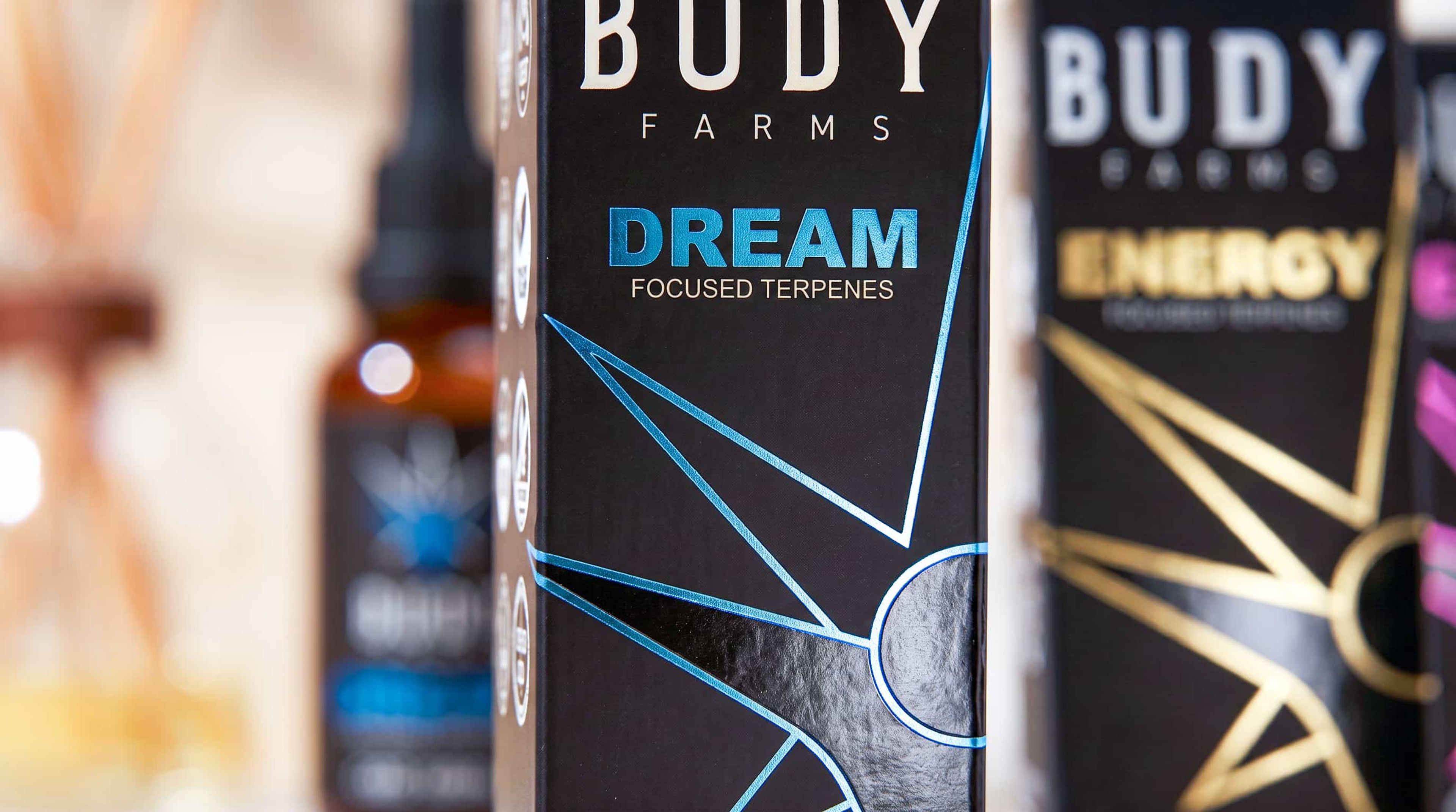 Close-up of a black Budy Farms Dream box showcasing metallic blue text and a geometric foil sunburst design.