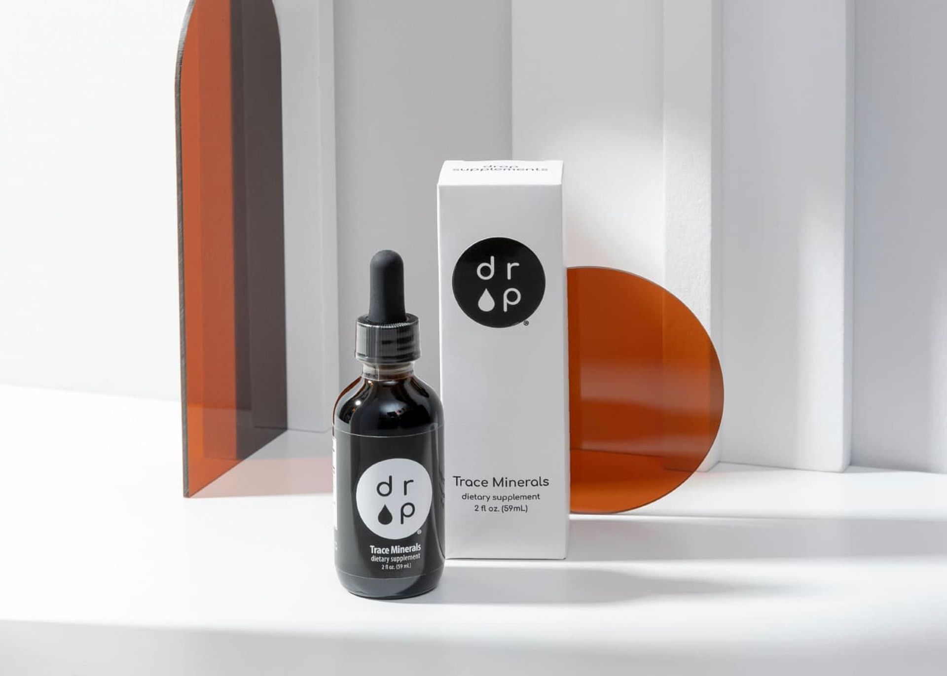 A black Drop Supplement Trace Minerals bottle standing in front of its matching white folding carton.