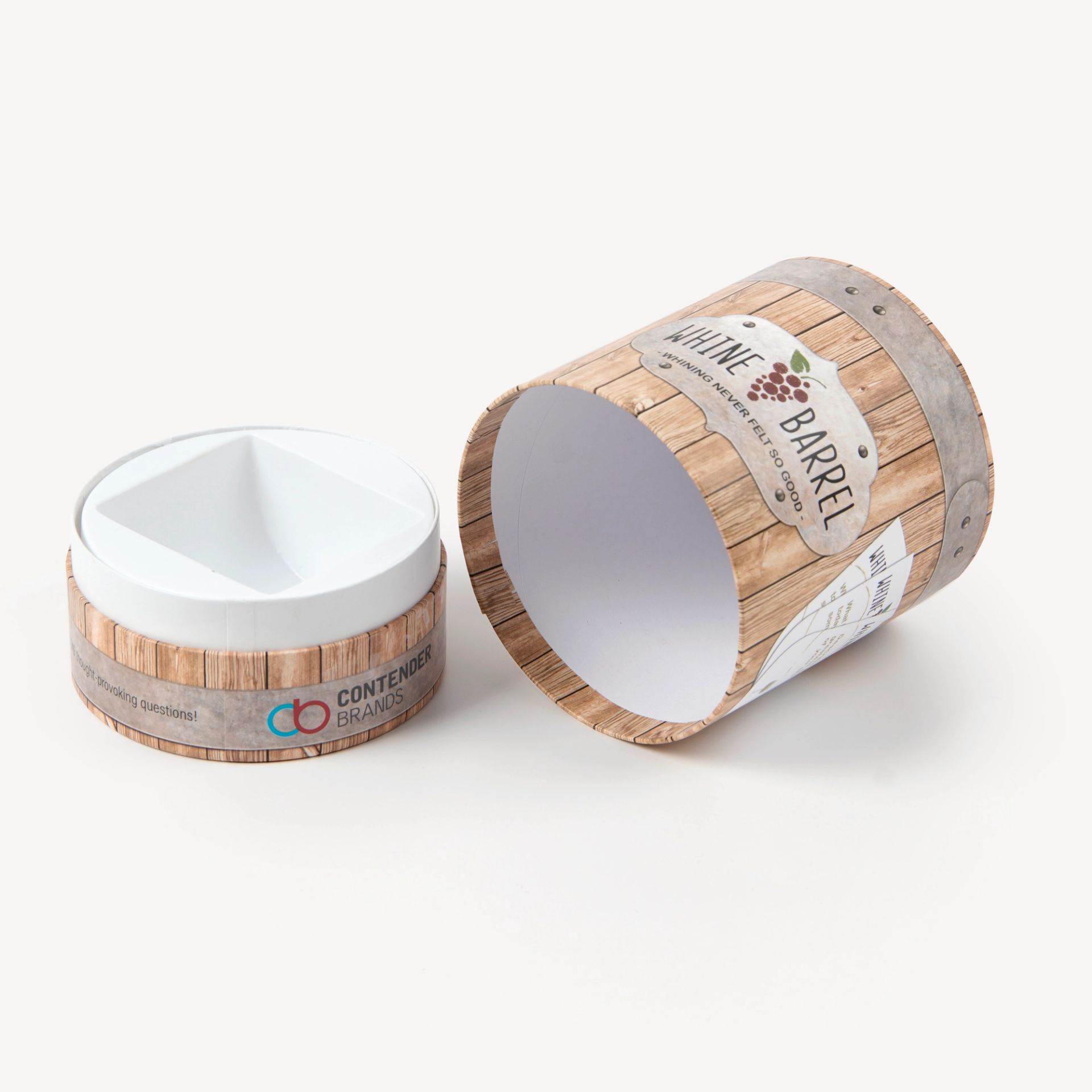 An empty open Whine Barrel game tube showing the custom molded inner tray and wood-grain graphics.