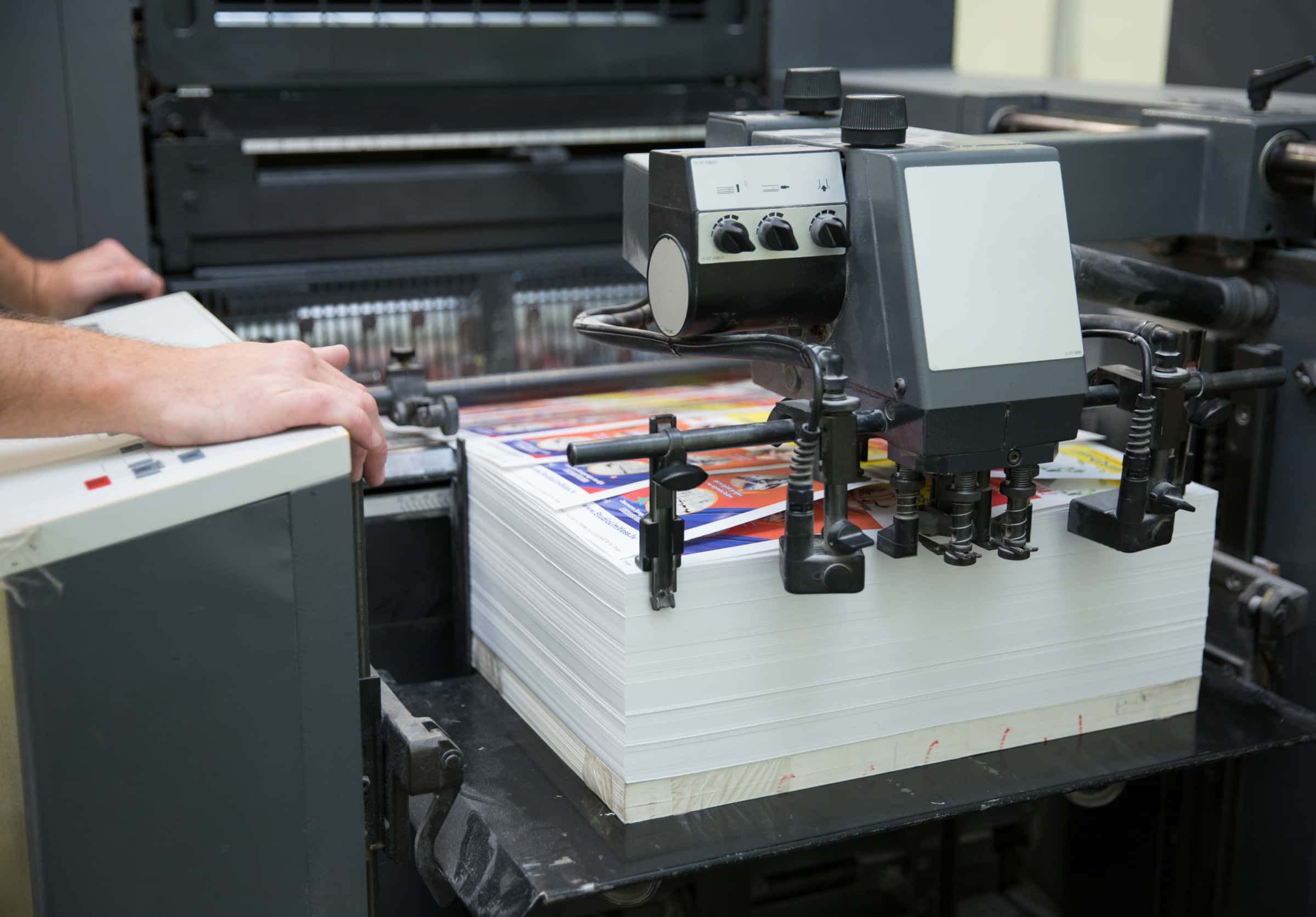 Sheet fed offset printing machine with sheets of paper.