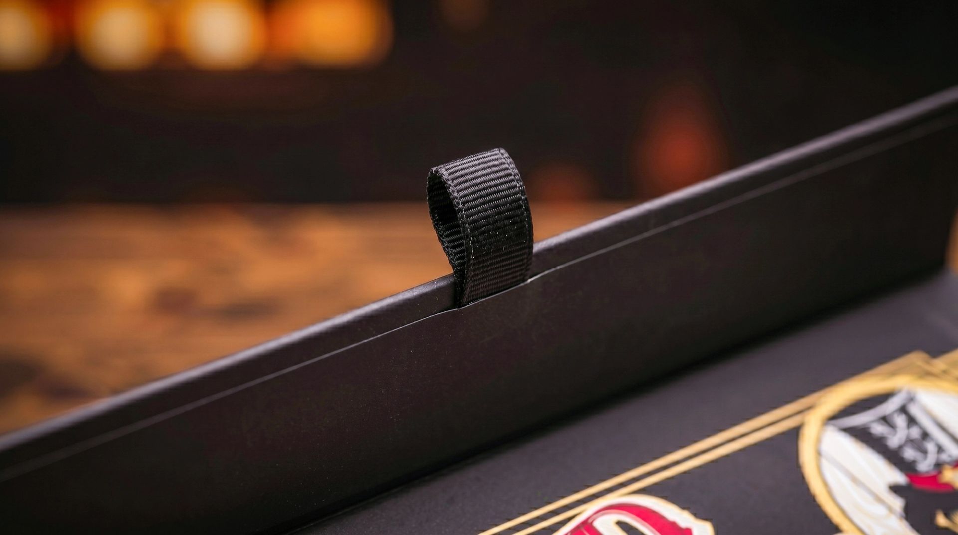 Close-up of the black woven ribbon pull tab on the edge of the magnetic rigid packaging box.