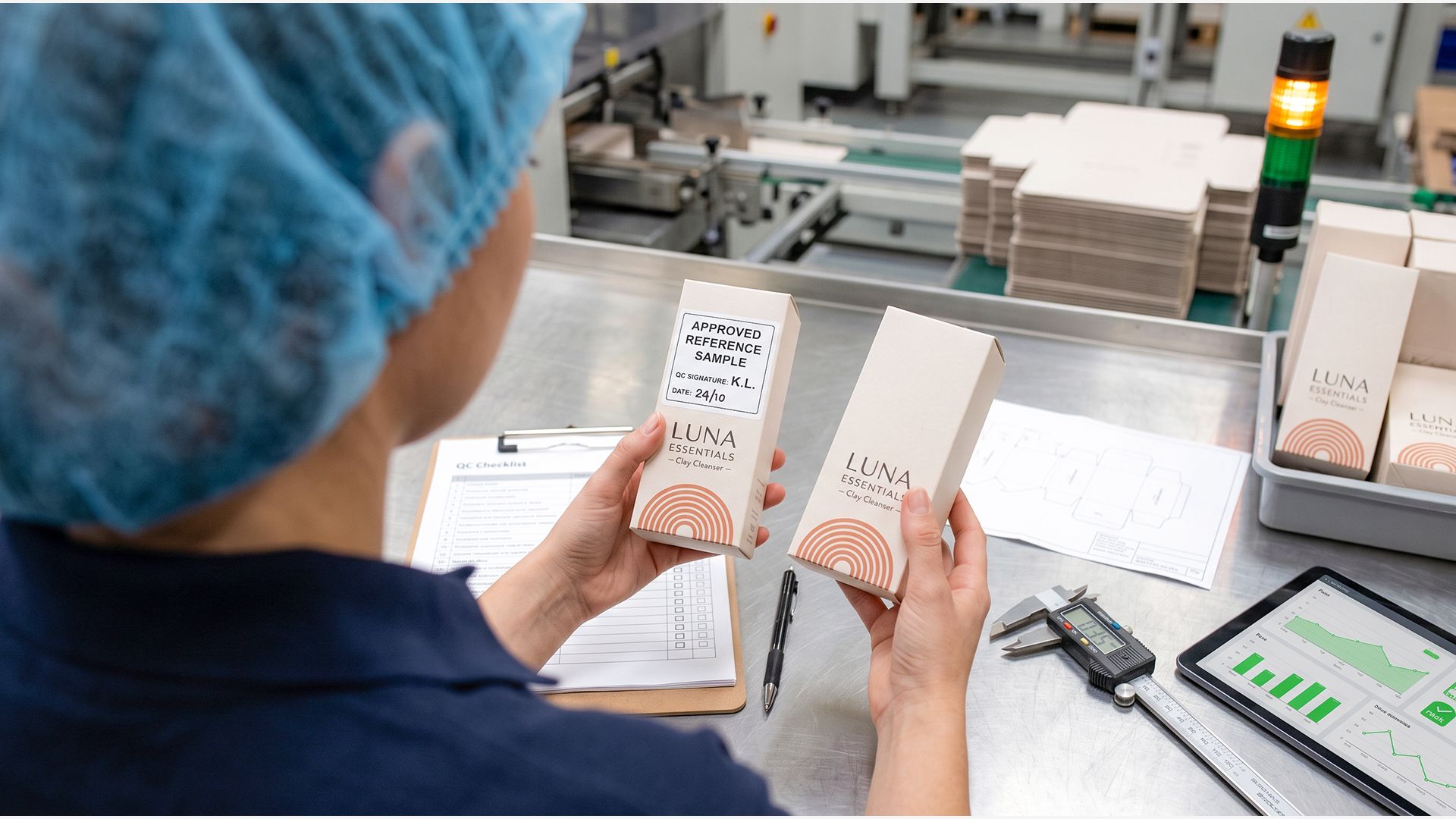 A quality inspector at a bench comparing a production package against an approved reference sample.