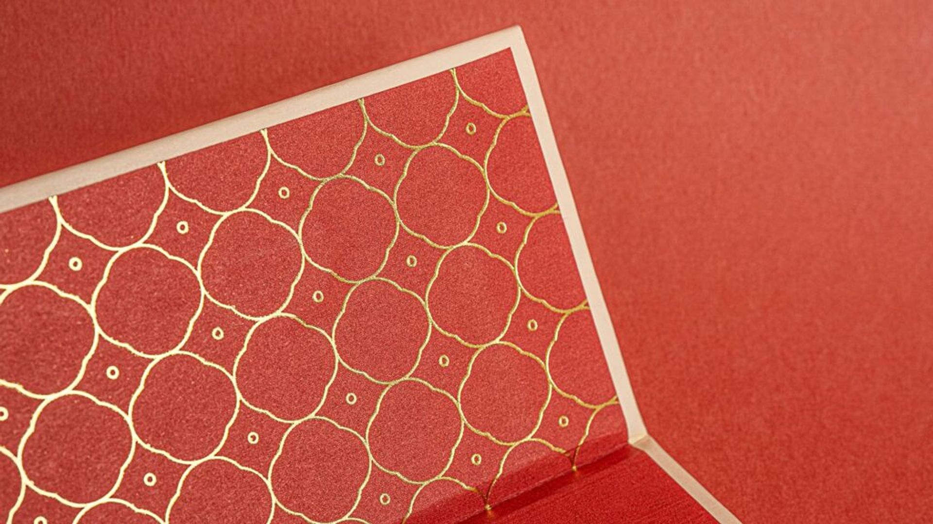 Close-up of the elegant repeating gold foil geometric pattern on the red interior lid flap.
