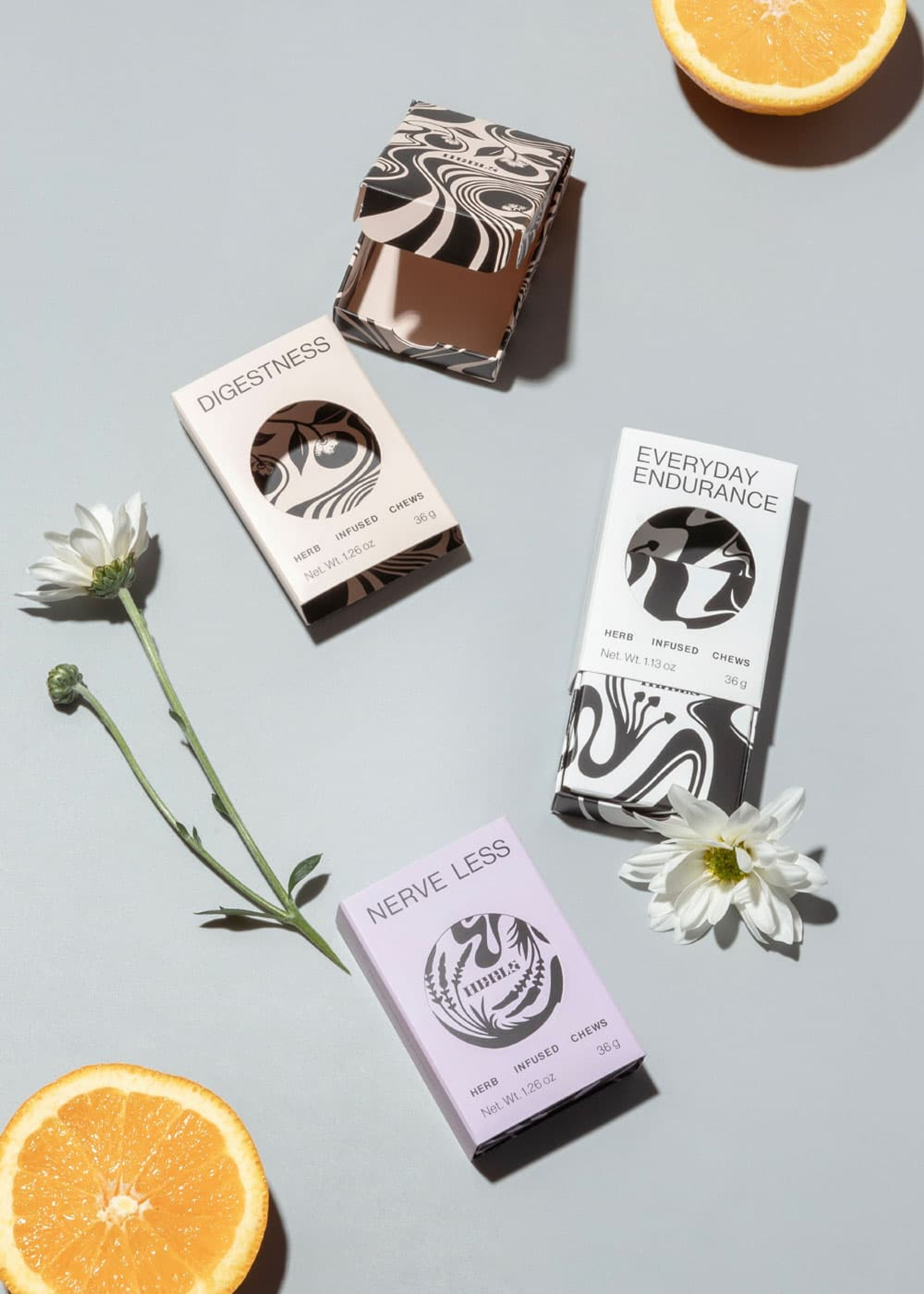 Top-down view of three HRBLS boxes, one open and two closed, styled with daisies and an orange half.