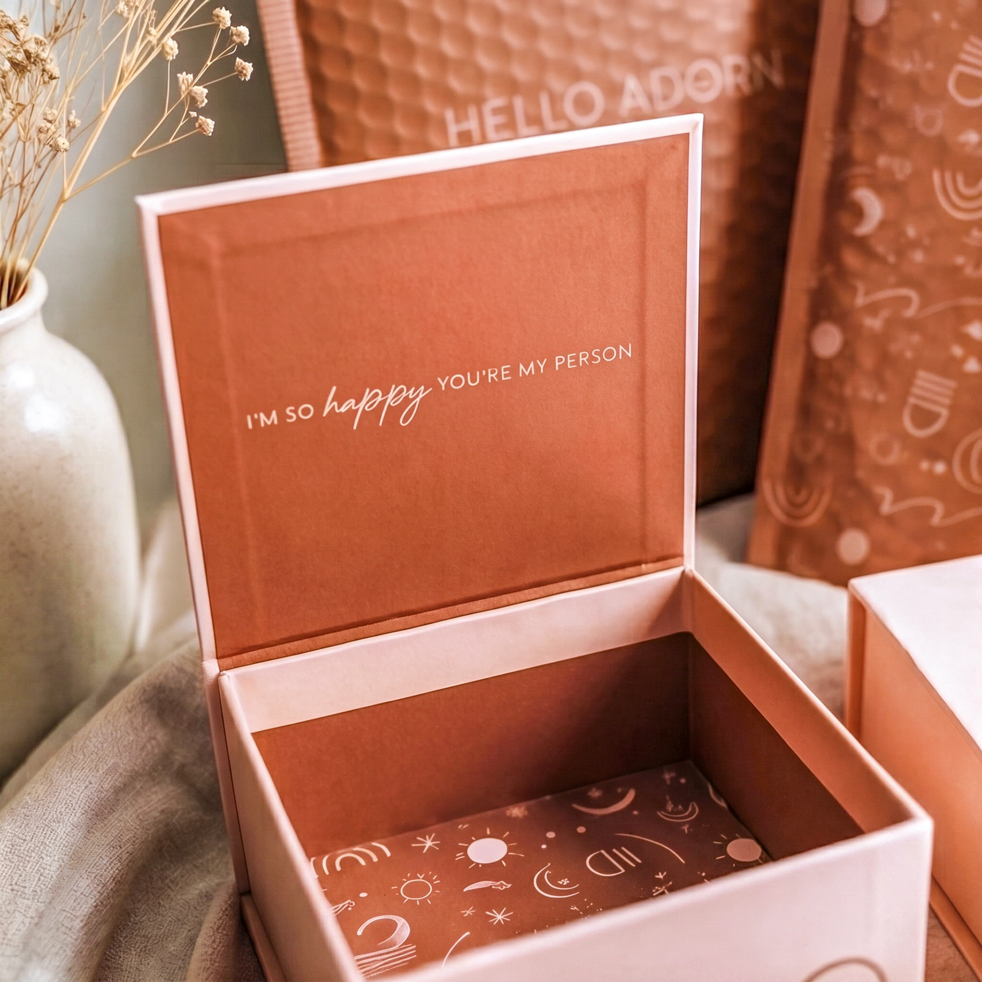 An open light pink gift box. The rust-colored inside lid has the phrase "I'M SO happy YOU'RE MY PERSON" printed in white.
