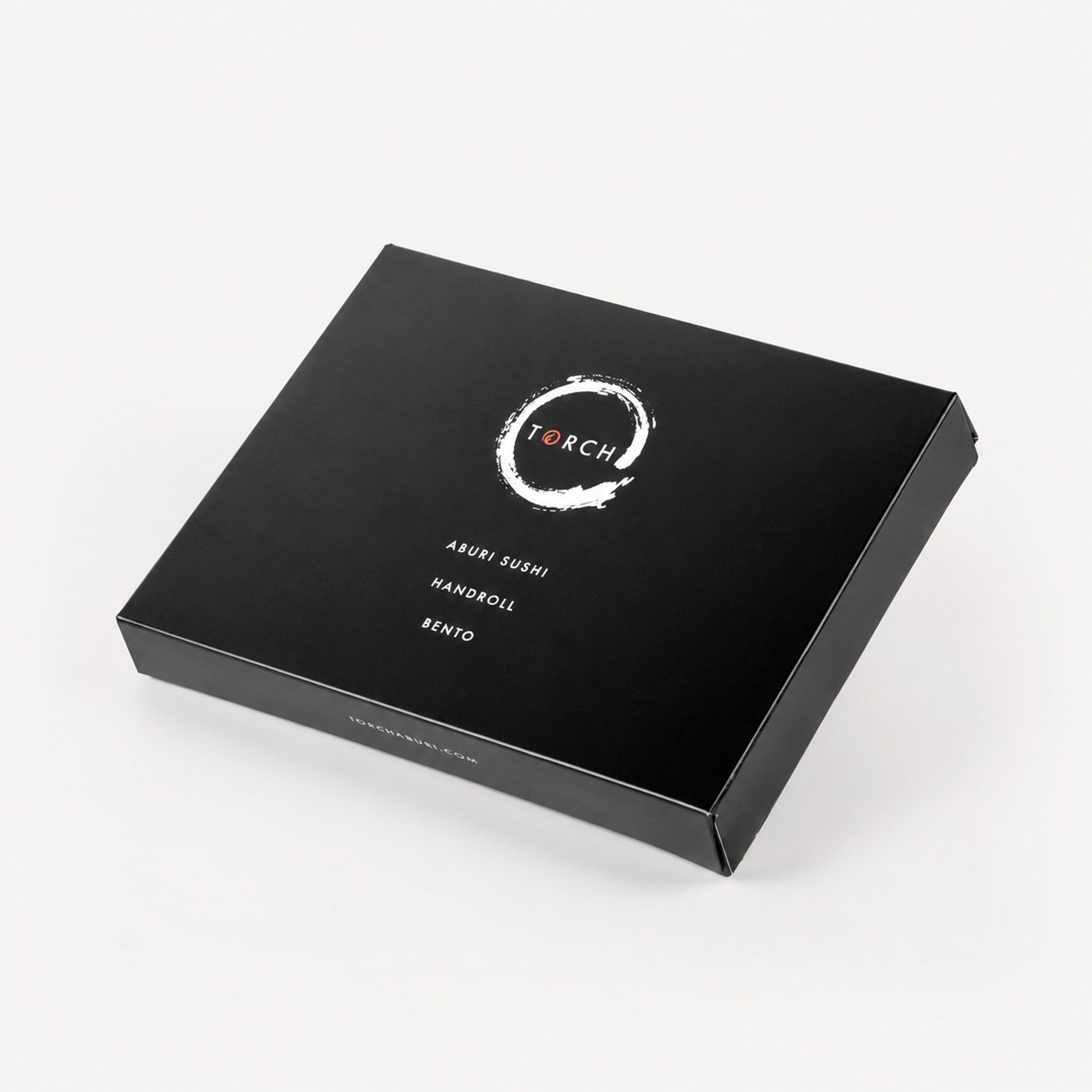 Closed black Torch Sushi bento box angled against a seamless white background, displaying the brand logo and text.