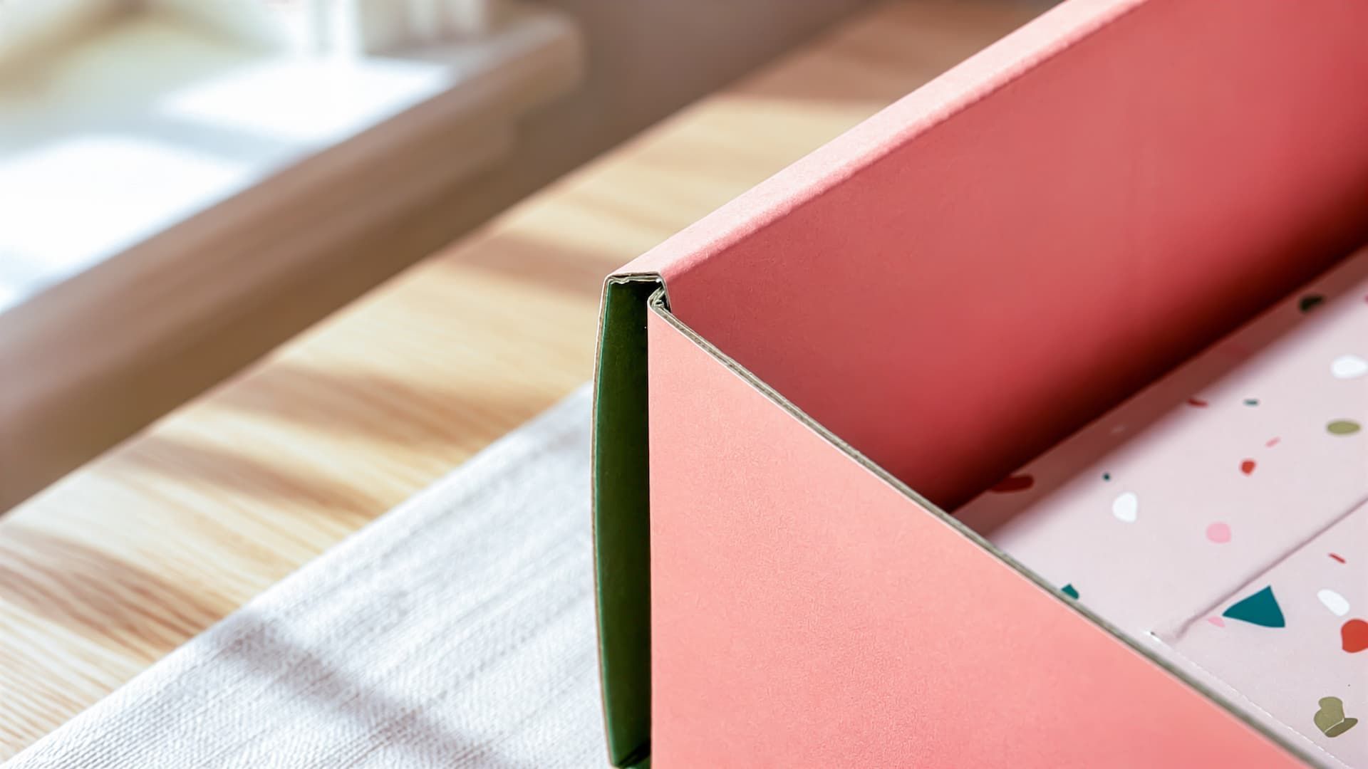 Close-up of a Semaine mailer box corner, showing the sturdy corrugated edges, coral exterior, and green interior.