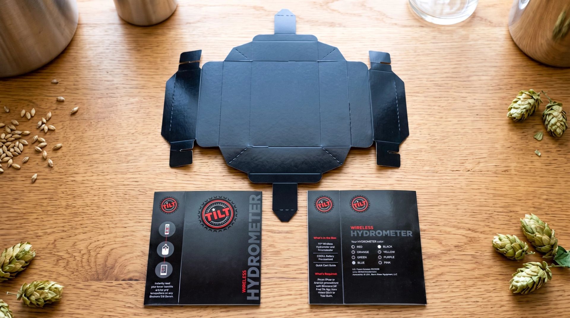 Unassembled TILT box die-cut template displayed flat next to two instruction cards, hops, and brewing grains.