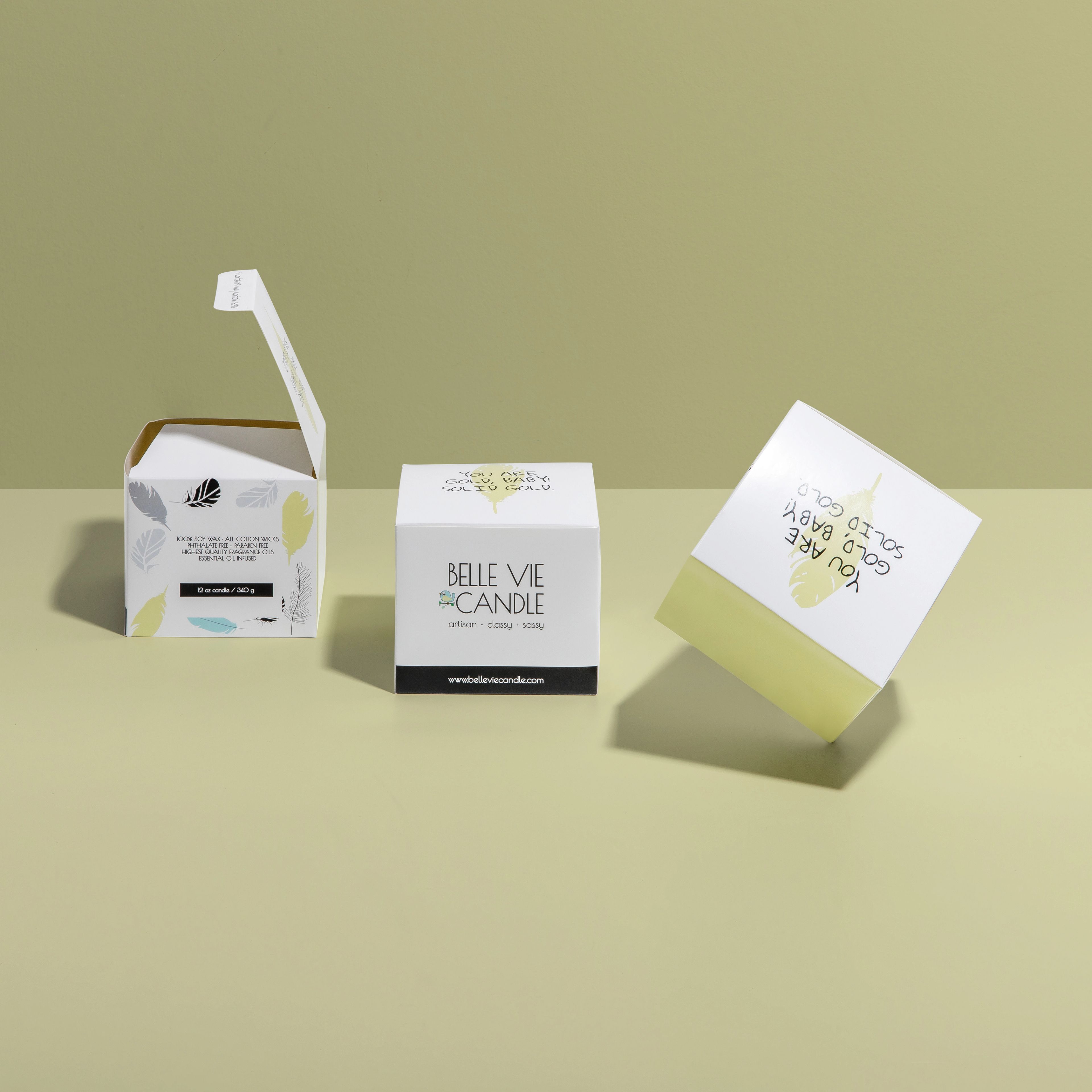 Three Belle Vie Candle boxes showing different angles, including the front logo, feather side pattern, and top messaging.