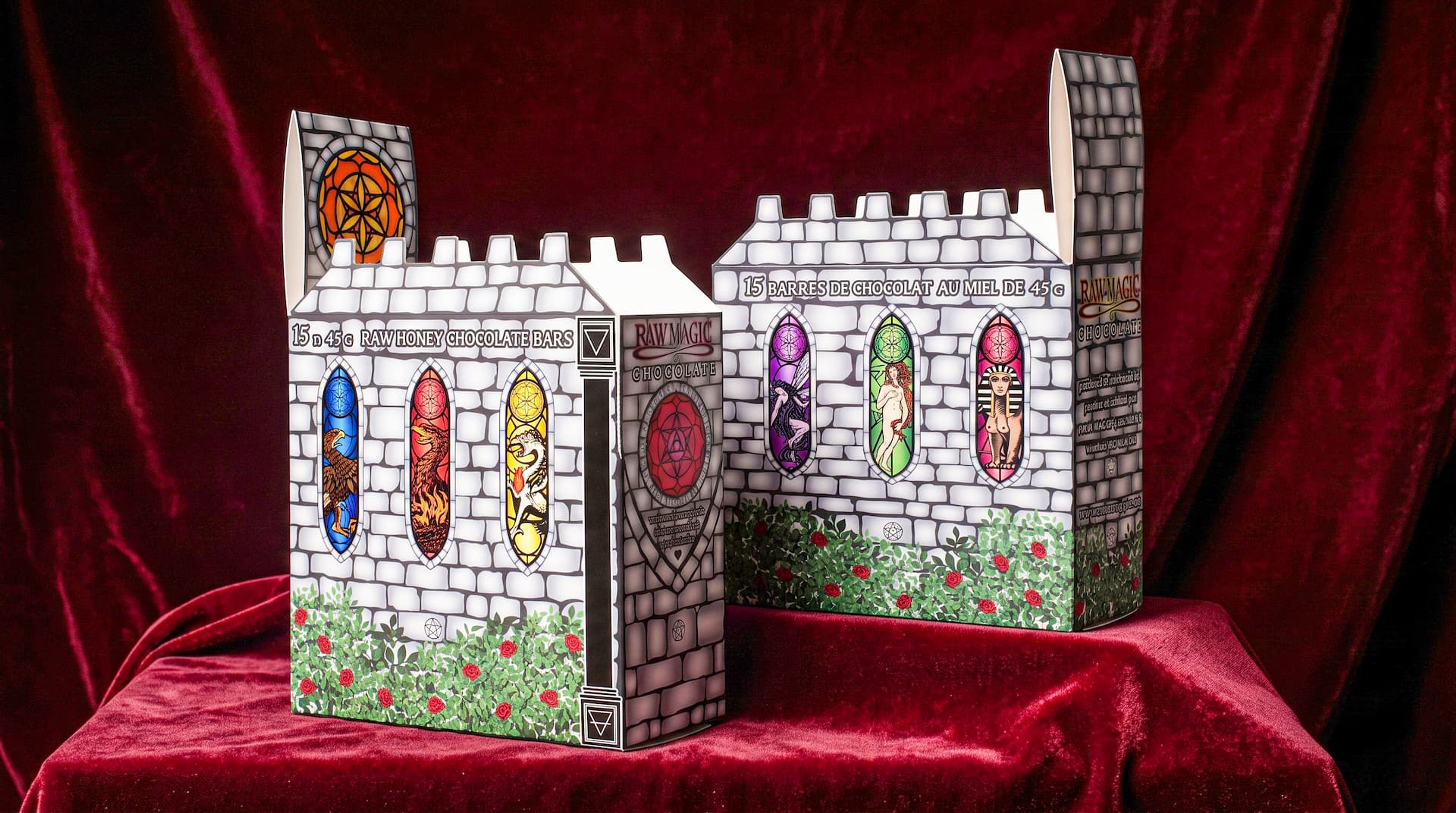 Two castle-shaped Raw Magic Chocolate display boxes with printed stone walls and stained glass on red velvet.