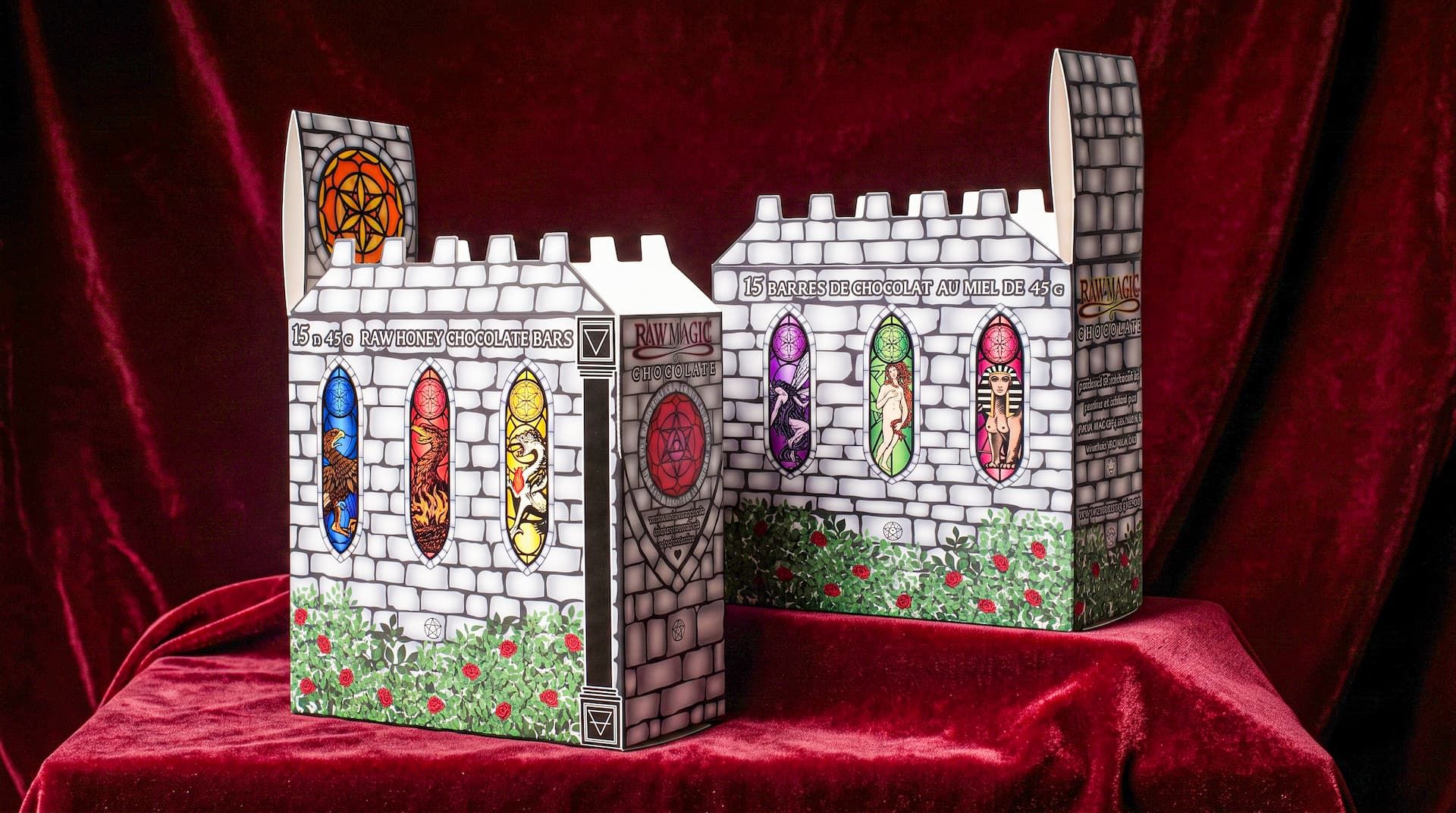 Two castle-shaped Raw Magic Chocolate display boxes with printed stone walls and stained glass on red velvet.