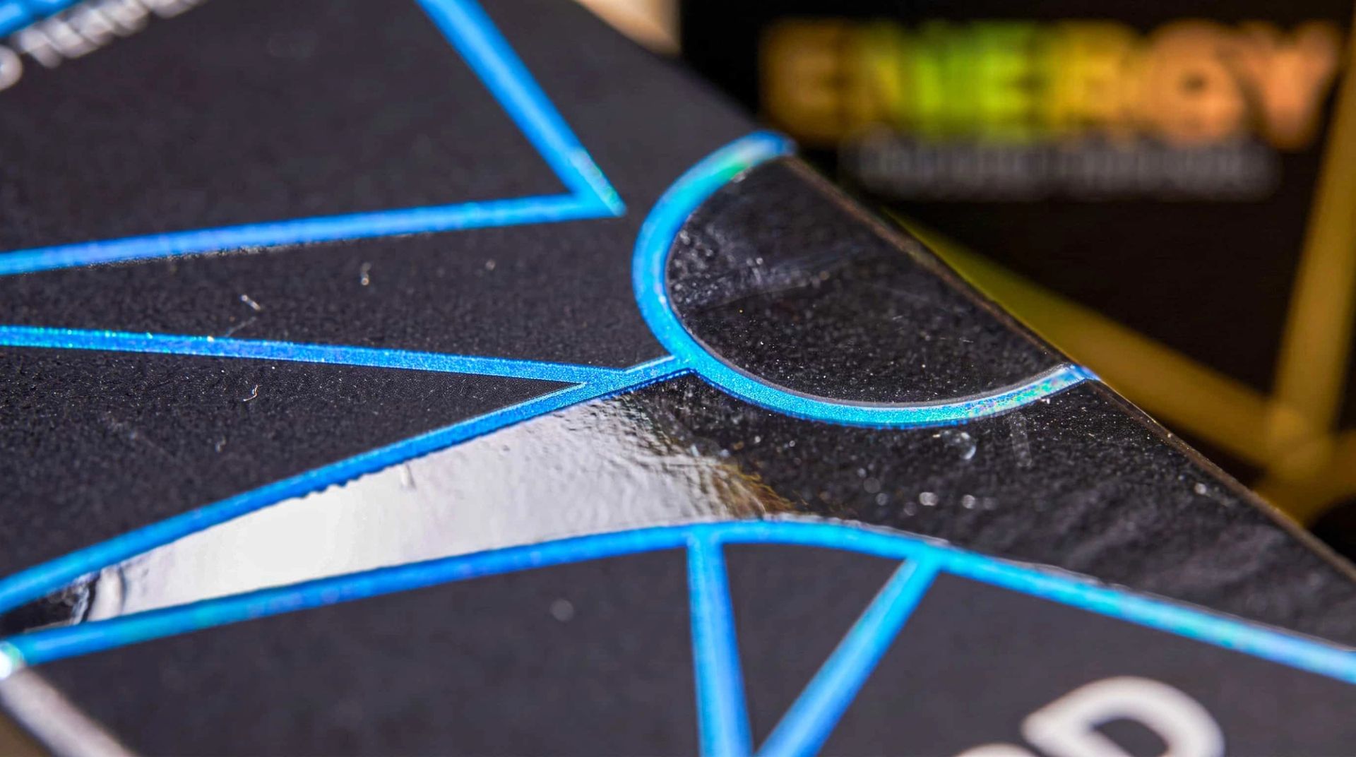 Extreme close-up of a black Budy Farms box showing the raised, glossy texture of the blue foil stamping.