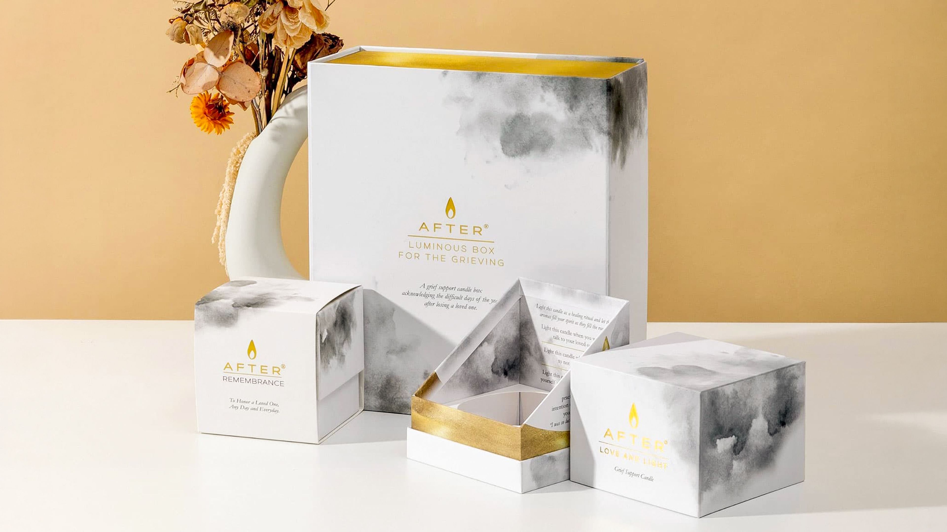 AFTER Luminous Box for the Grieving and candle boxes featuring grey watercolor clouds and gold foil stamping.