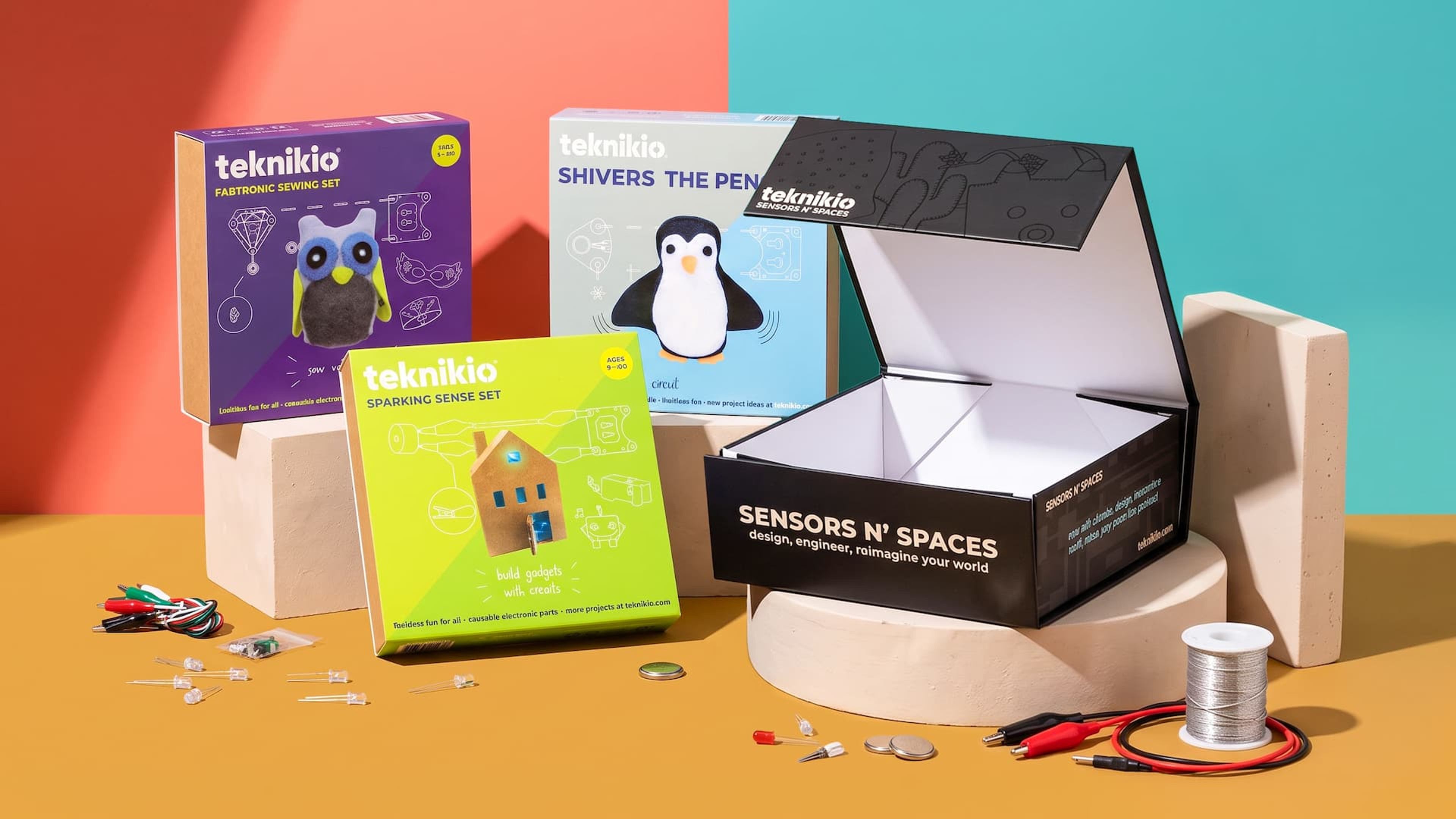 Collection of colorful Teknikio STEM kit boxes, featuring an open black magnetic closure box alongside craft components.
