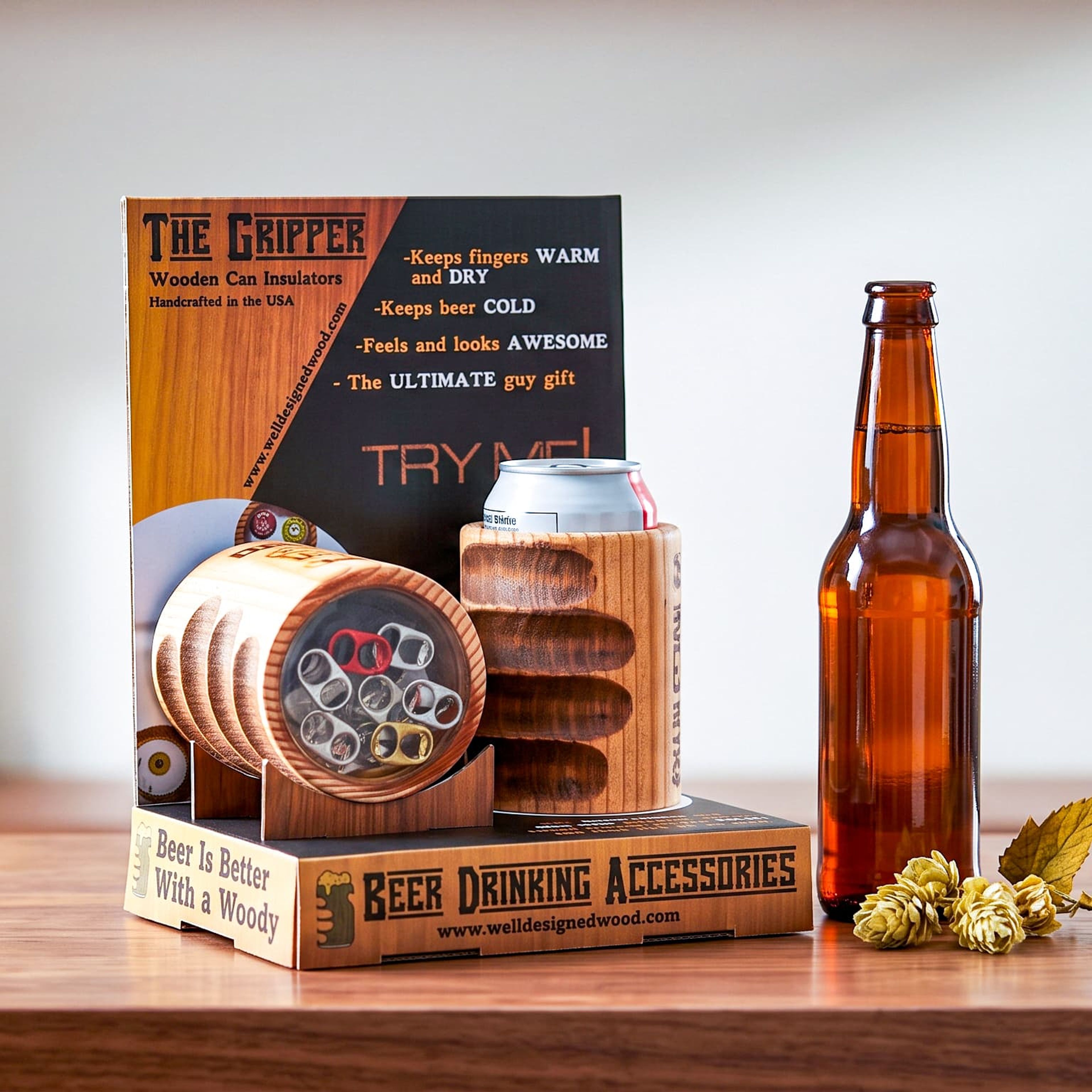 Retail display for Well Designed Wood's wooden can insulators holding two wooden koozies, next to a beer bottle and hops.