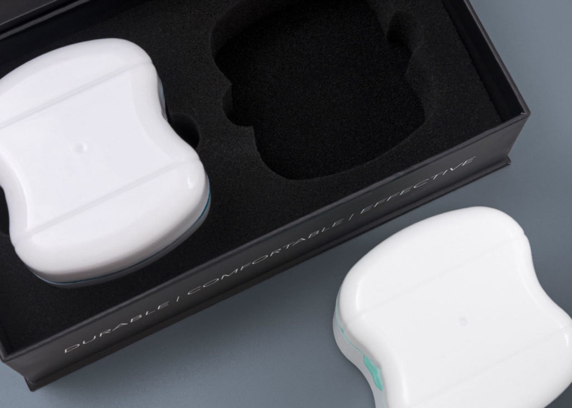 Close-up of a dual-cavity black foam insert holding a white Serena Sleep case, with another case outside the box.