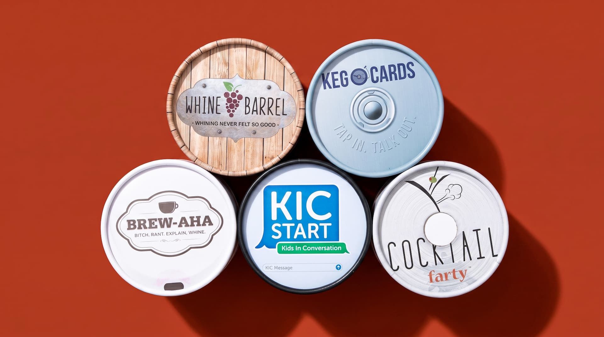 Top-down view of five custom printed circular lids for conversation card games arranged on a terracotta background.