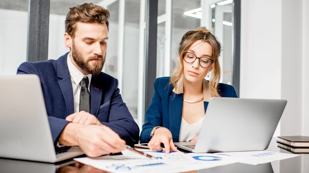 Analytics team working with paper charts and laptops at the office