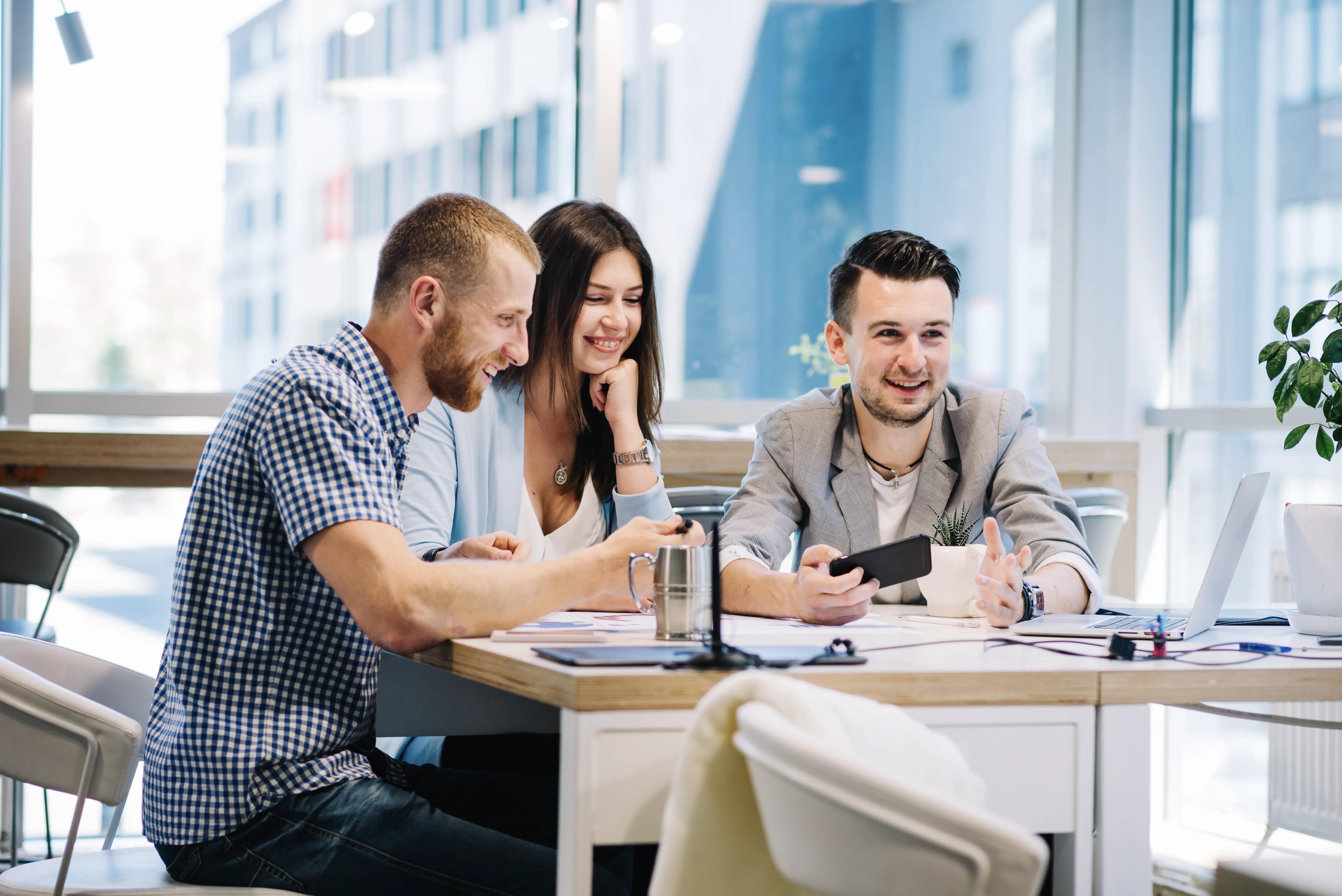 Cheerful colleagues engaged in a lively discussion over a new work strategy at a bright office space