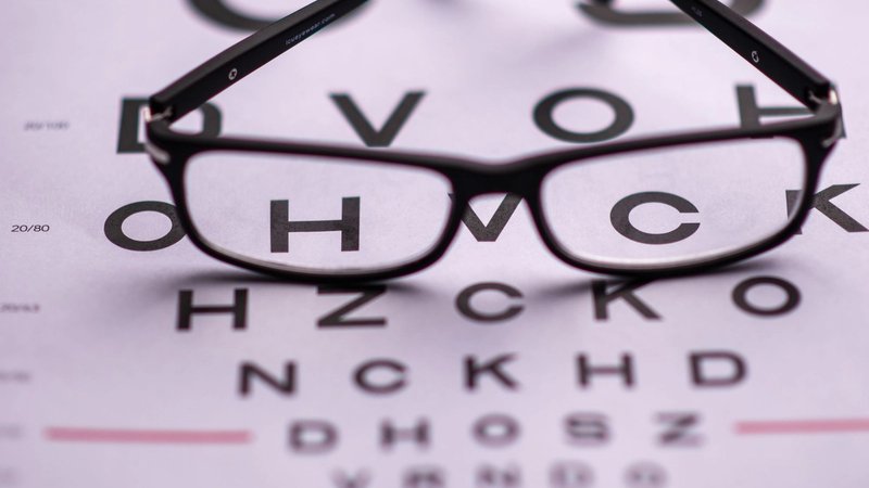 Eyeglasses resting on an eye test chart
