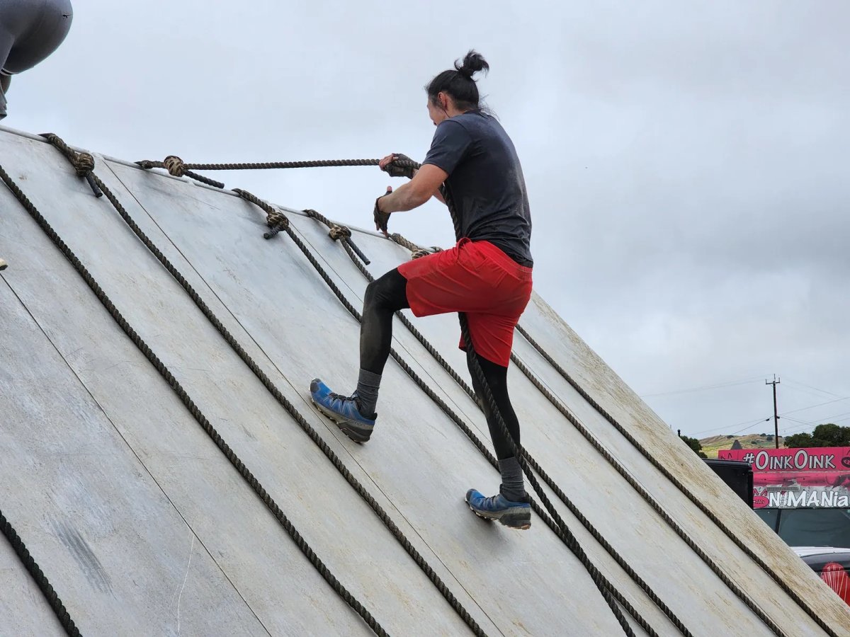 Christopher climbing a rope obstacle outdoors