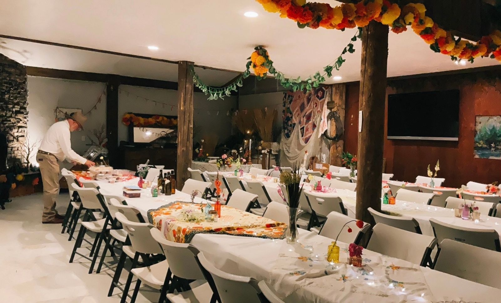 Long tables set inside the Bourbon Barn under garlands of orange and yellow marigolds, the last place settings being laid