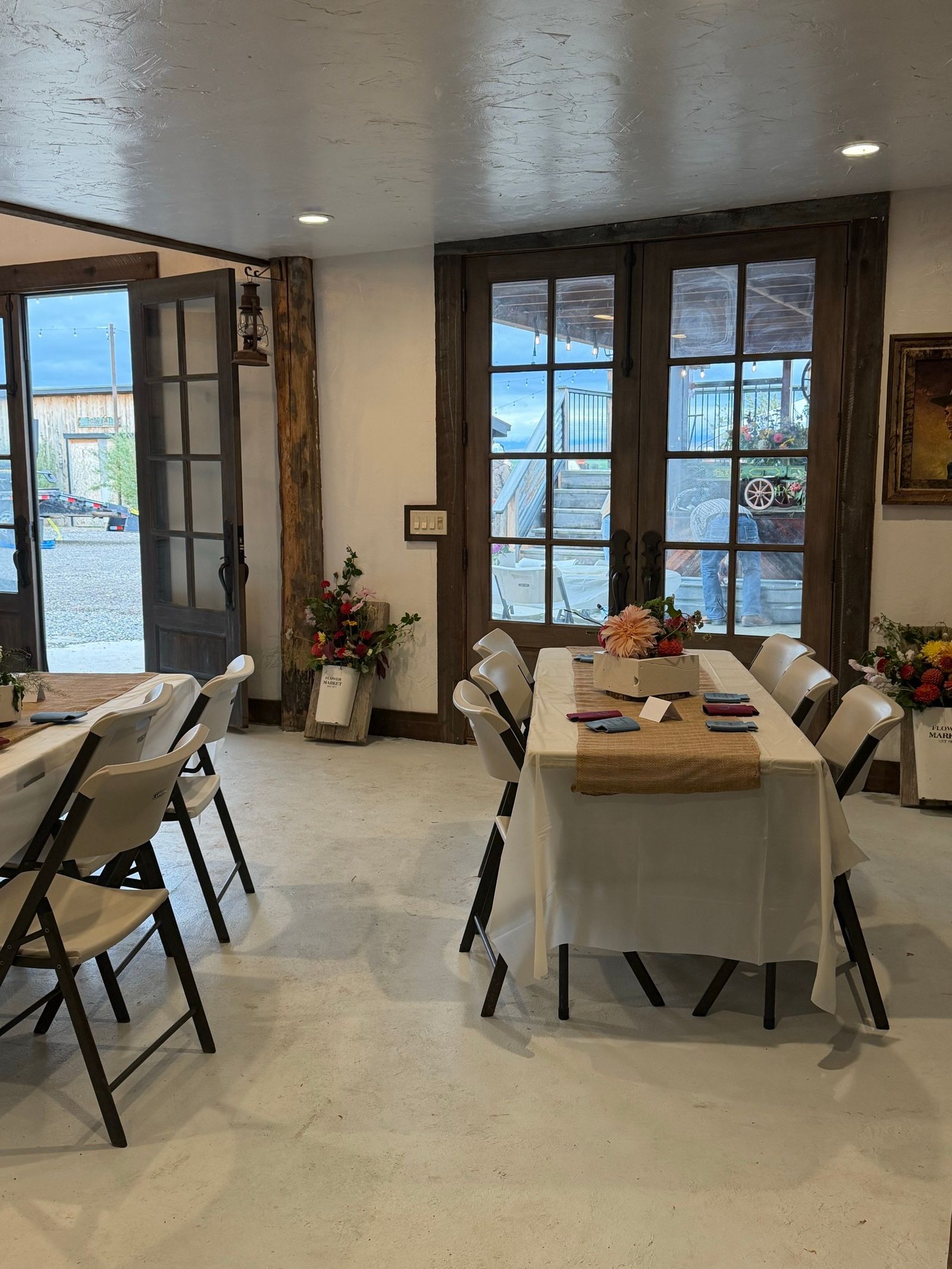 Tables in white linen and burlap by the French doors inside the Bourbon Barn, farm flowers on every table