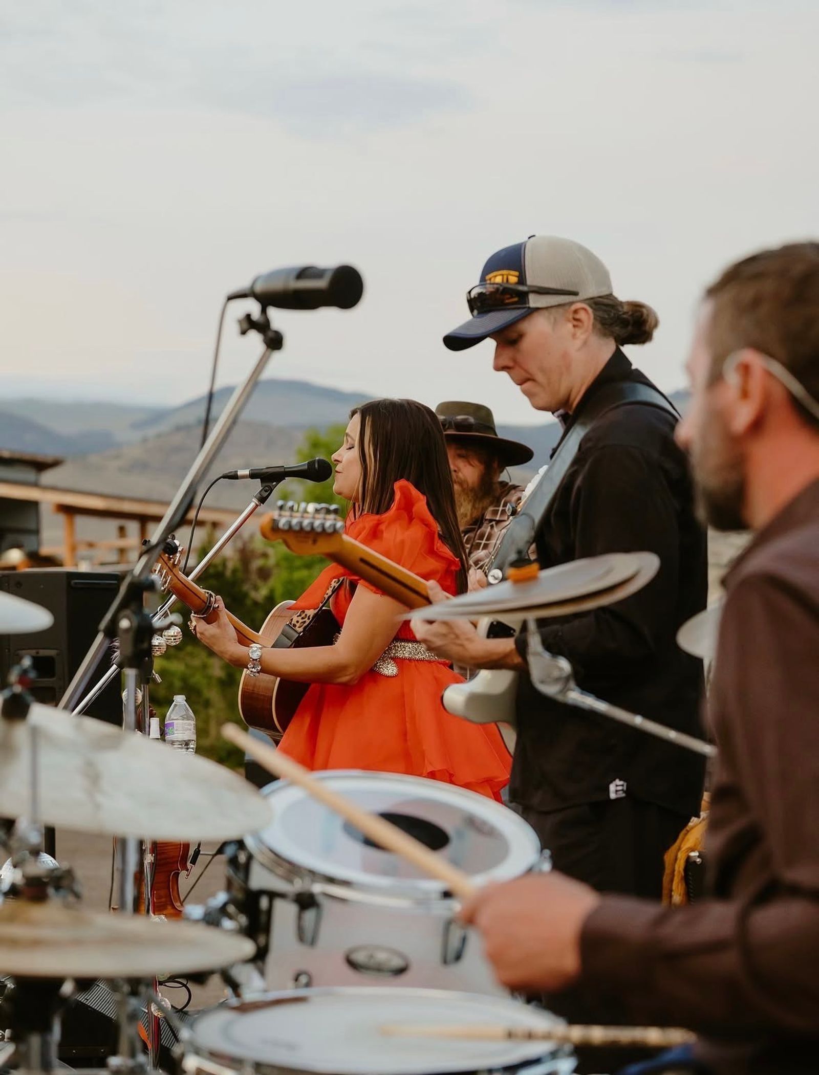 The band playing on the farm stage, the drummer in the foreground and the hills behind