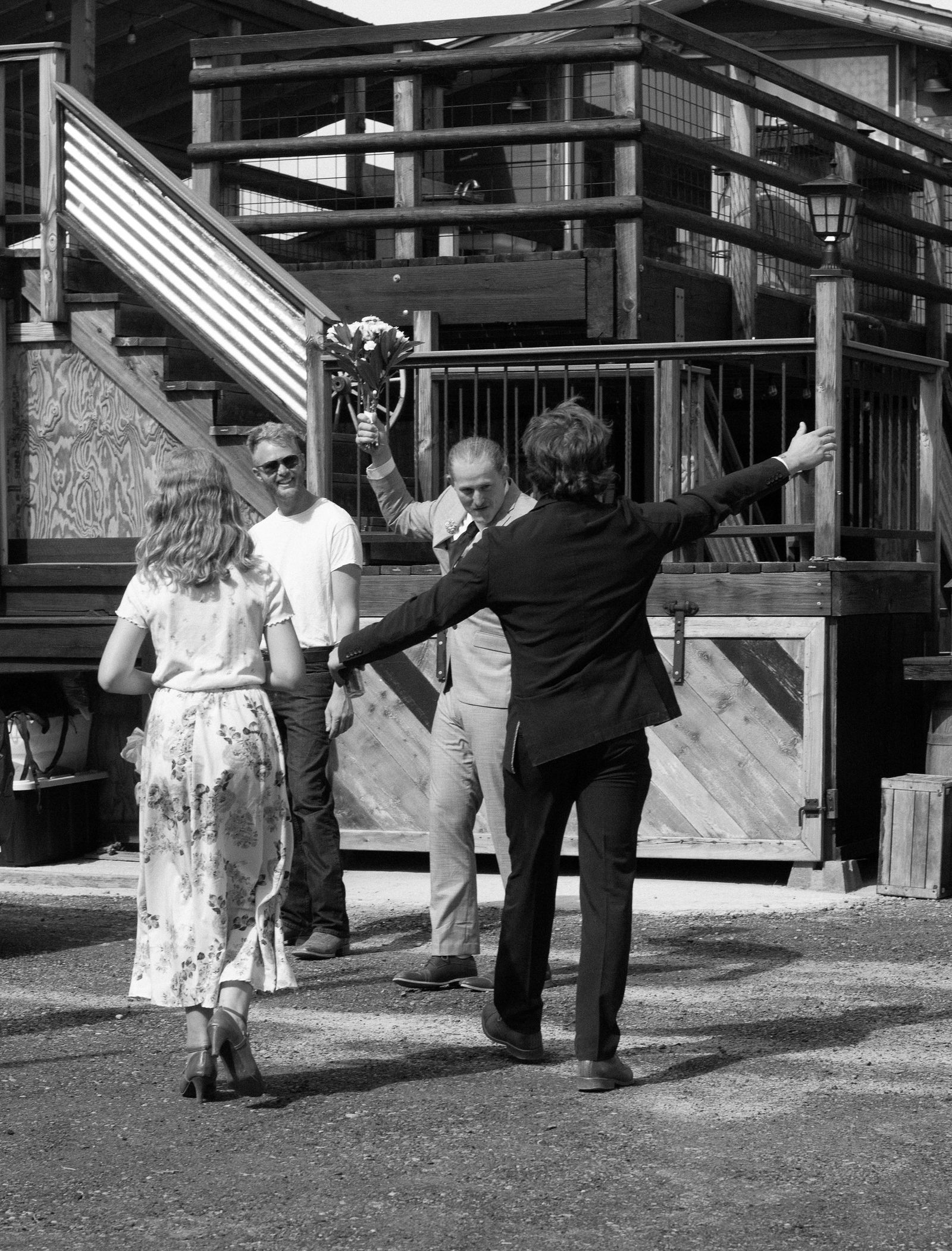 A groom raises a bouquet in welcome as friends arrive by the Bourbon Barn deck