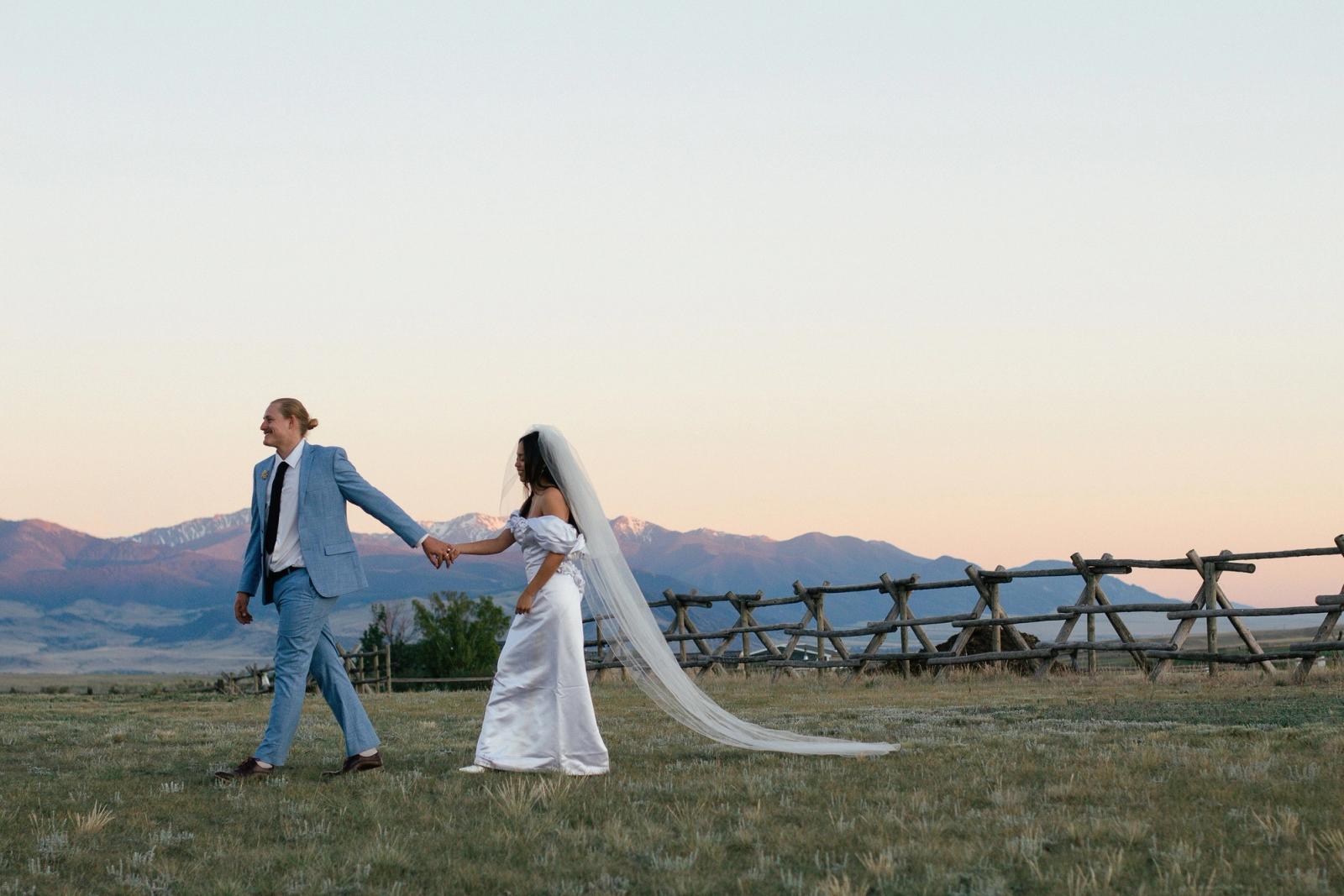 Walking hand in hand along the jackleg fence at sunset, the peaks lit pink behind them
