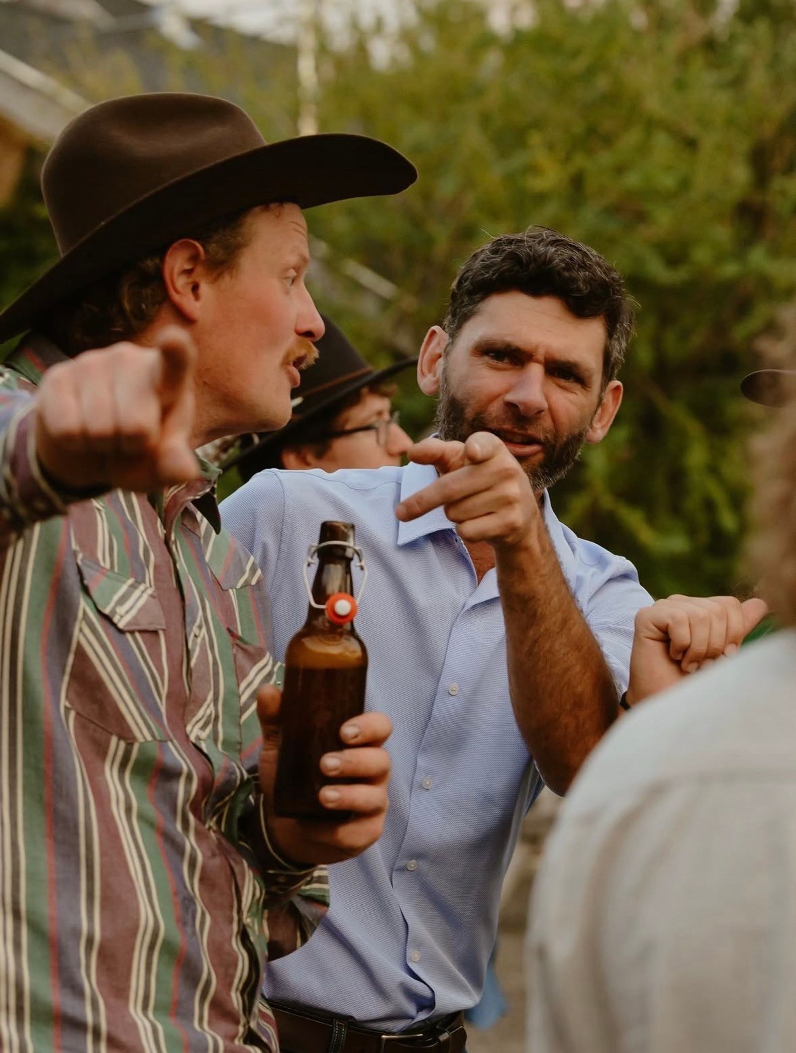 Two guests laughing and pointing across the yard mid-conversation