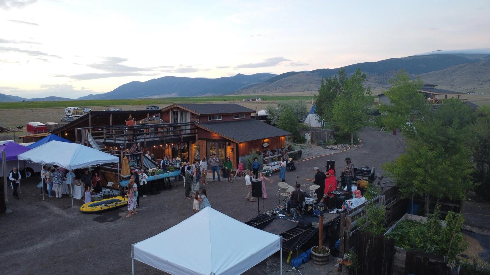 An evening party at the Bourbon Barn from above - lights on, a band playing, and guests dancing in the yard