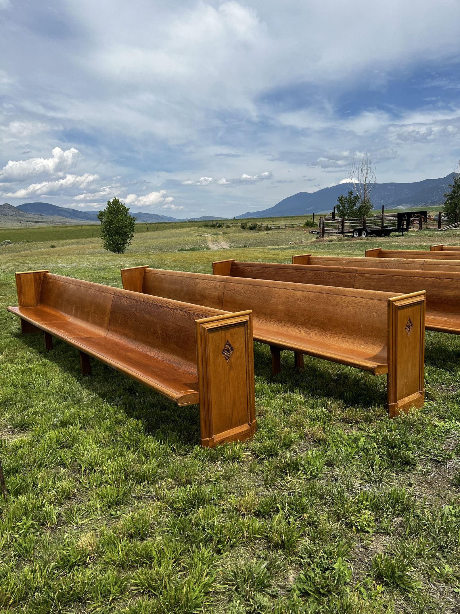 Wooden pews lined up in the green meadow, the mountains under a big sky