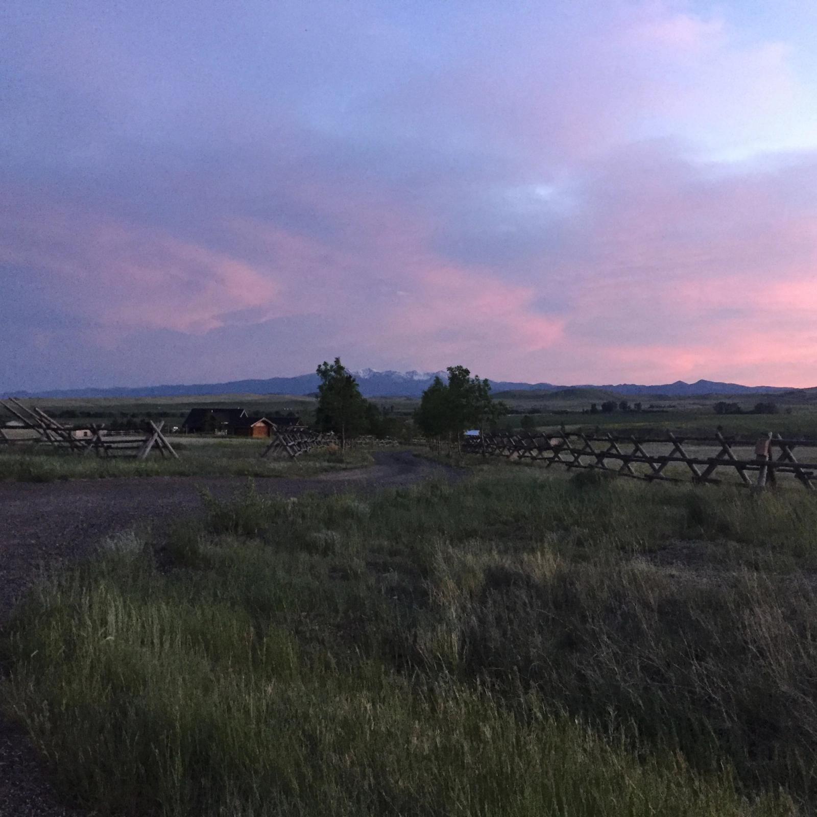 Pink evening sky over the lane and jackleg fences, snow on the mountains beyond
