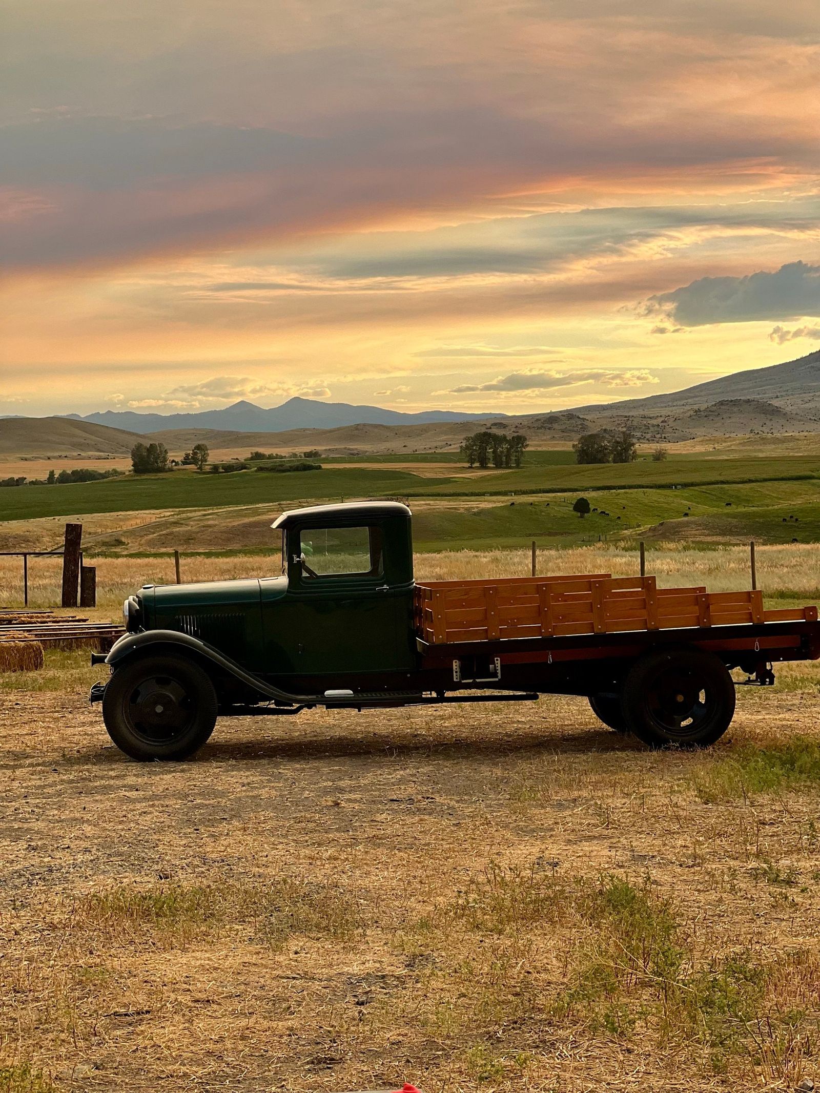 The farm's 1932 Ford flatbed truck parked in the field at sunset, the valley and mountains beyond