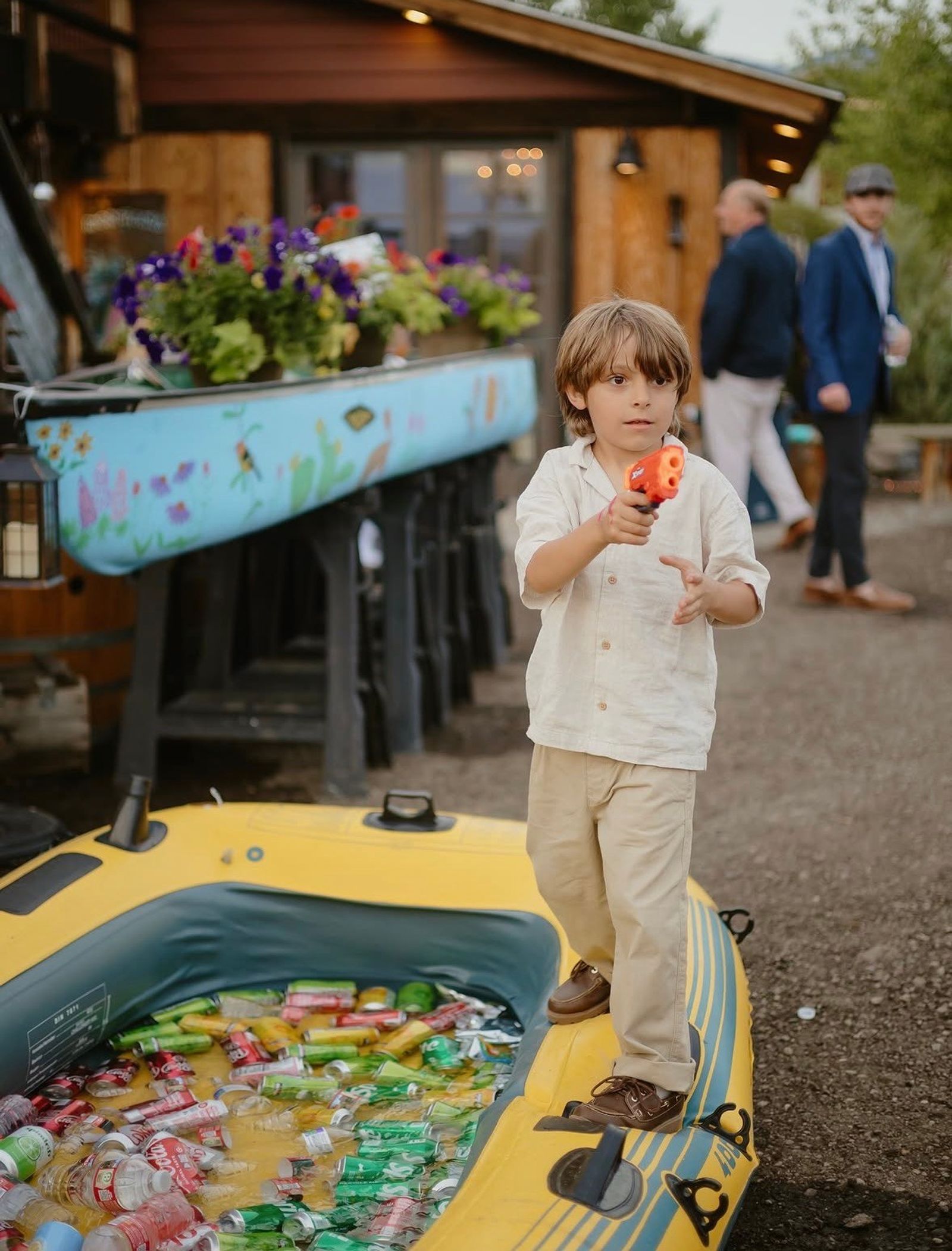 A young guest with a water pistol on the edge of an inflatable raft filled with iced drinks