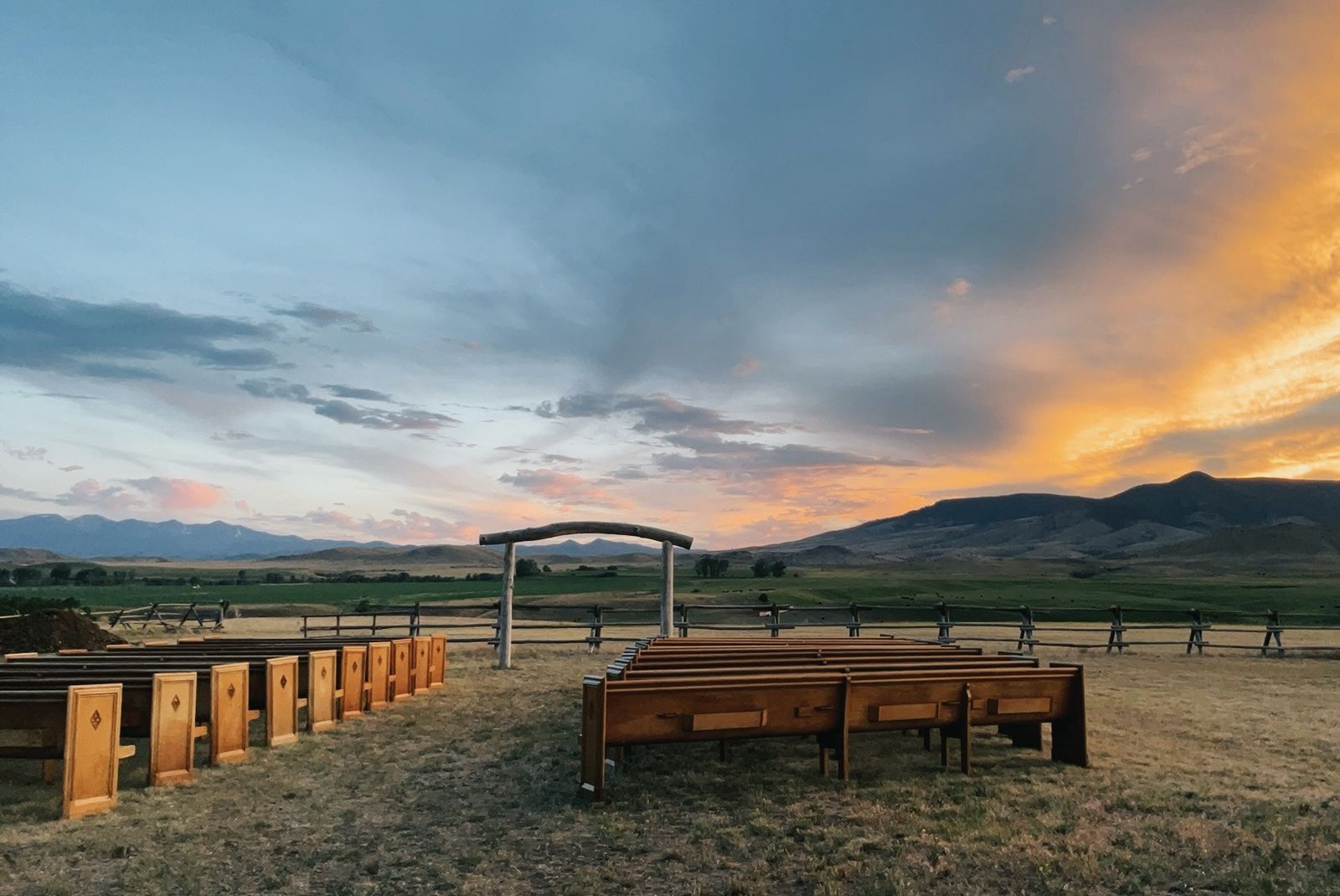 Handcrafted wooden pews and the handmade ceremony arch at sunset in the Ceremony Meadow